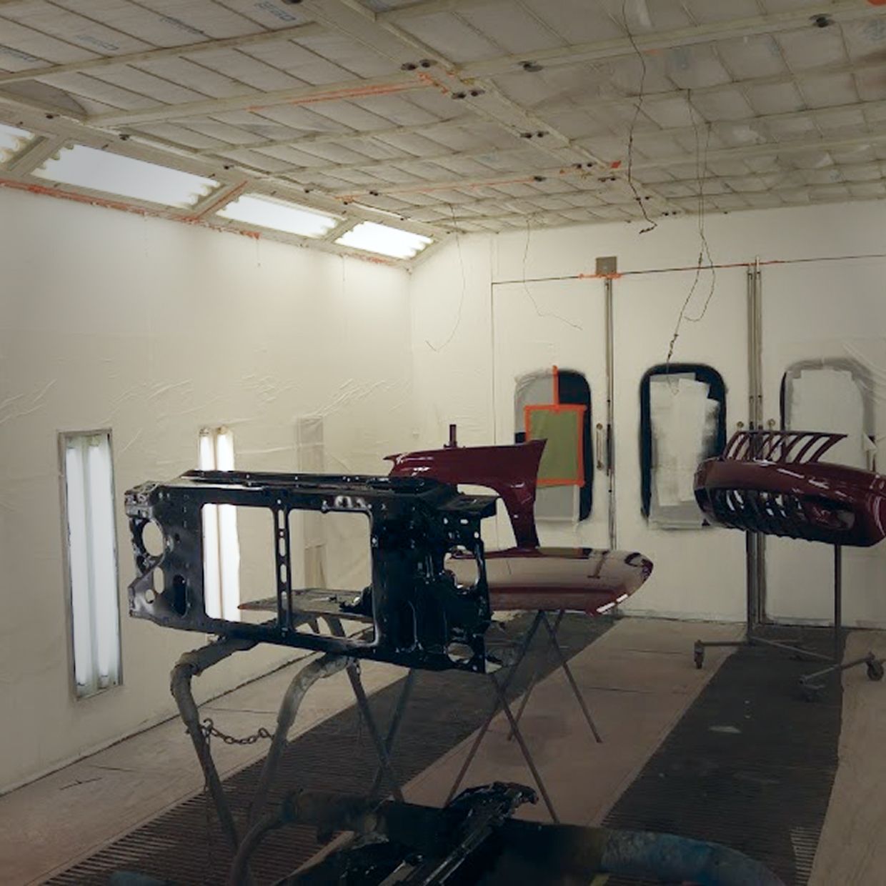 Car parts in a paint booth, with lights and ventilation. | Stu's Collision Center