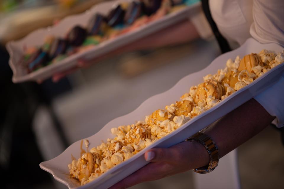 Person holding a tray of desserts topped with popcorn and caramel.
