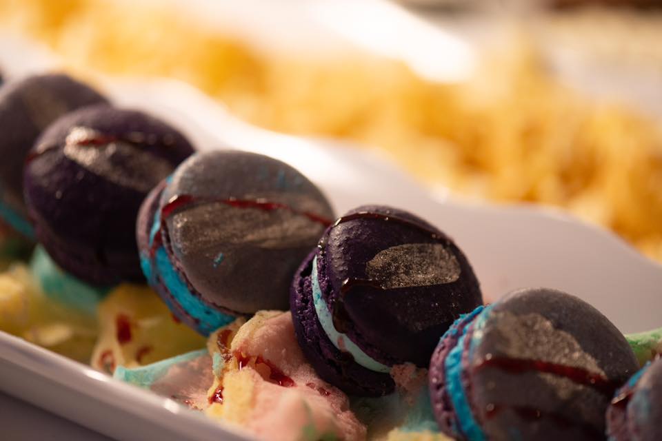 Colorful macarons on various ice cream scoops with syrup drizzle