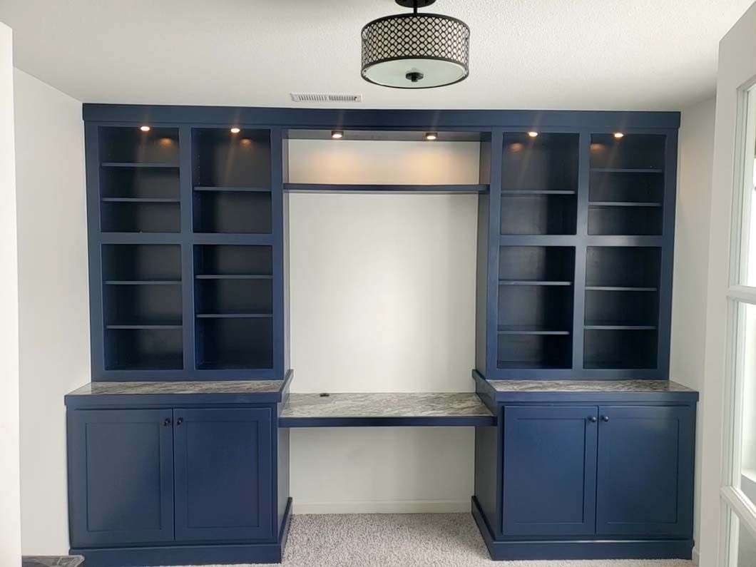 A room with blue cabinets and shelves and a ceiling light