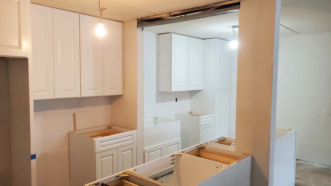 A kitchen under construction with white cabinets and a sink.