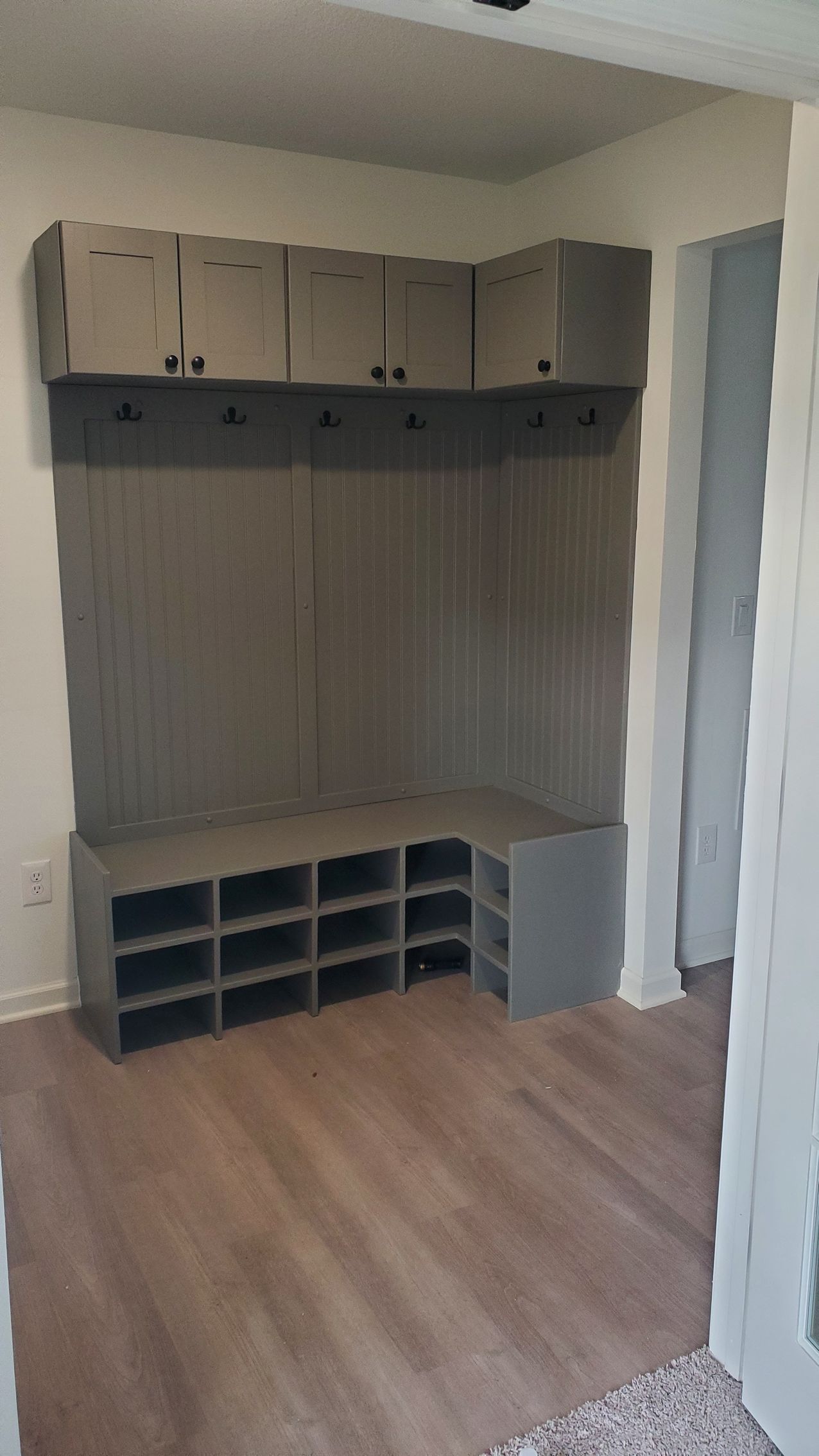 A room with a bench , shelves and cabinets in it.
