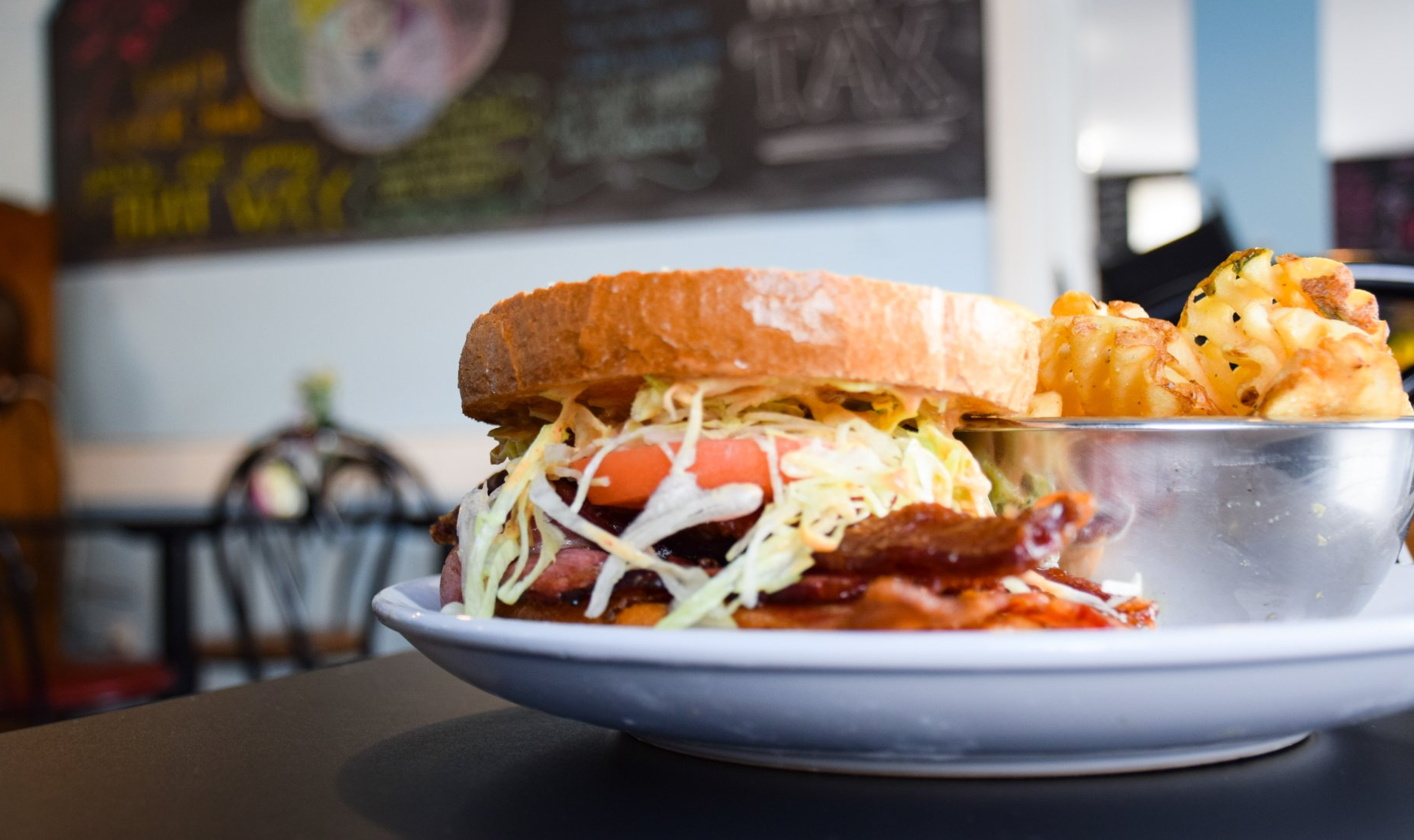 A sandwich and french fries are on a plate on a table.