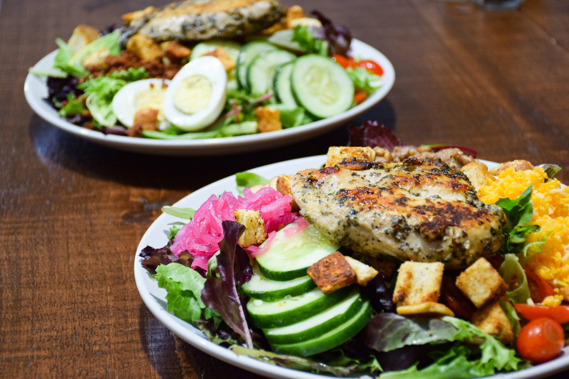 Two plates of food are sitting on a wooden table.