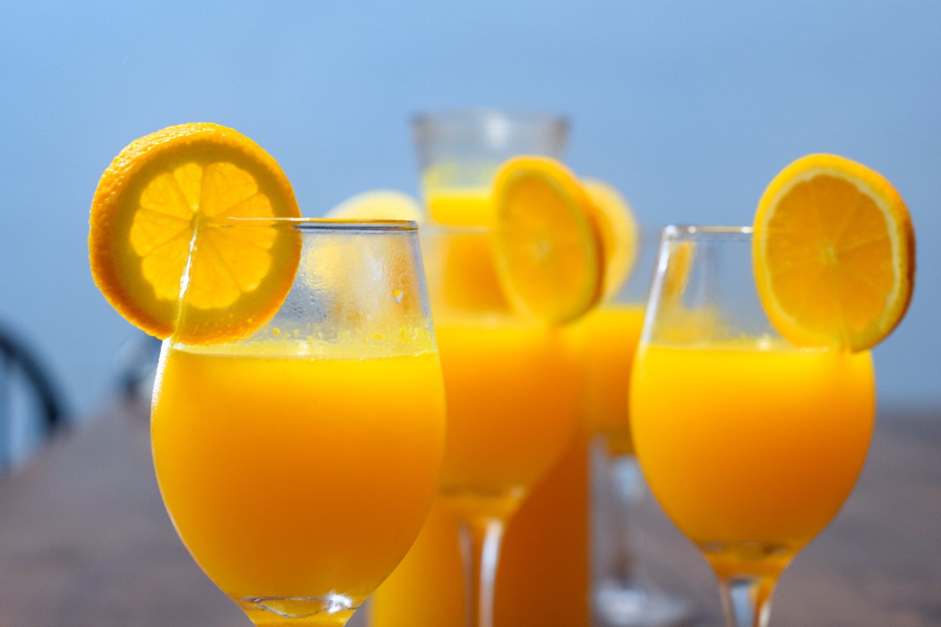 A pitcher of orange juice and glasses of orange juice on a table.