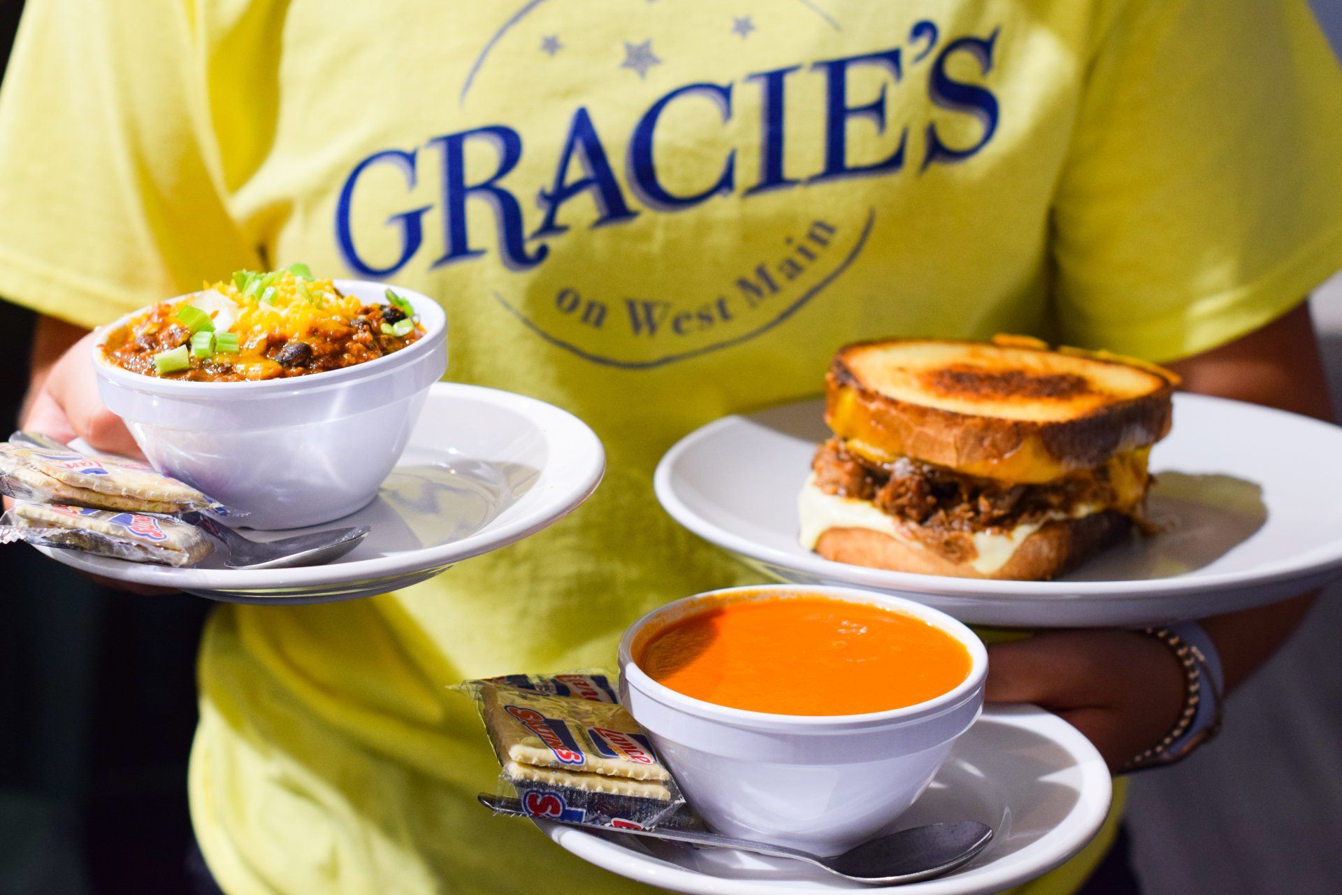 A person wearing a yellow shirt is holding plates of food.