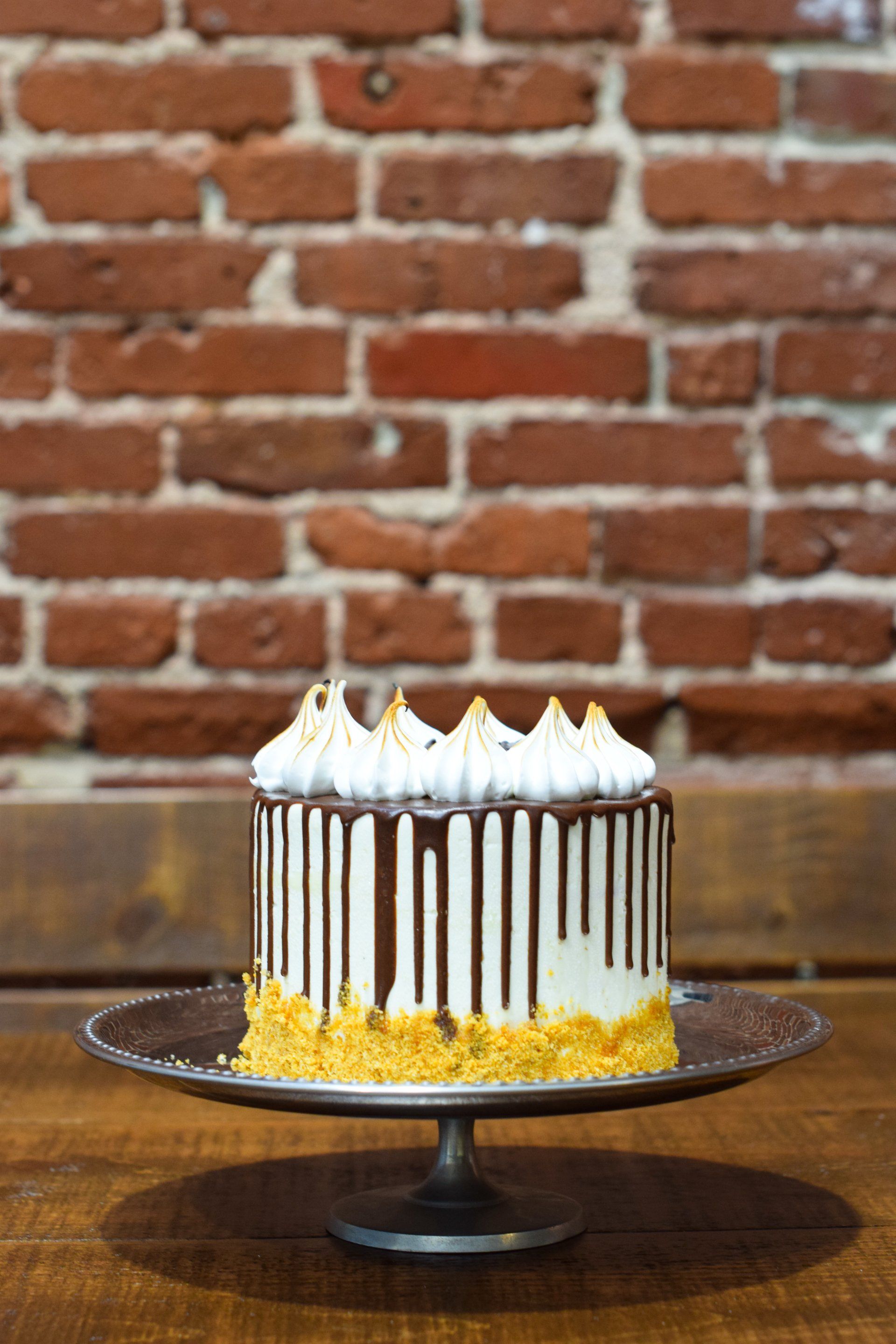 A cake on a plate with a brick wall in the background.