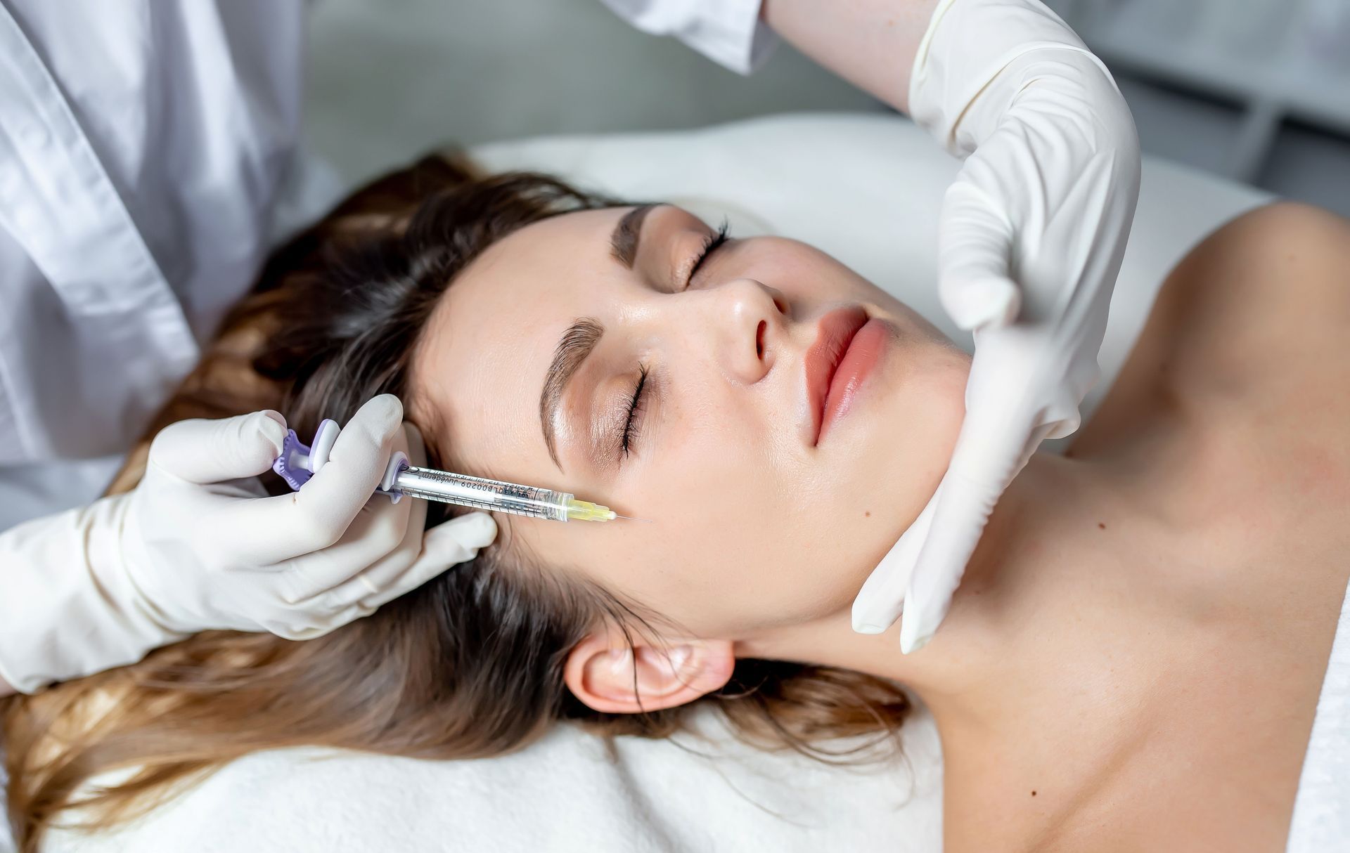 A woman is getting a botox injection in her face.