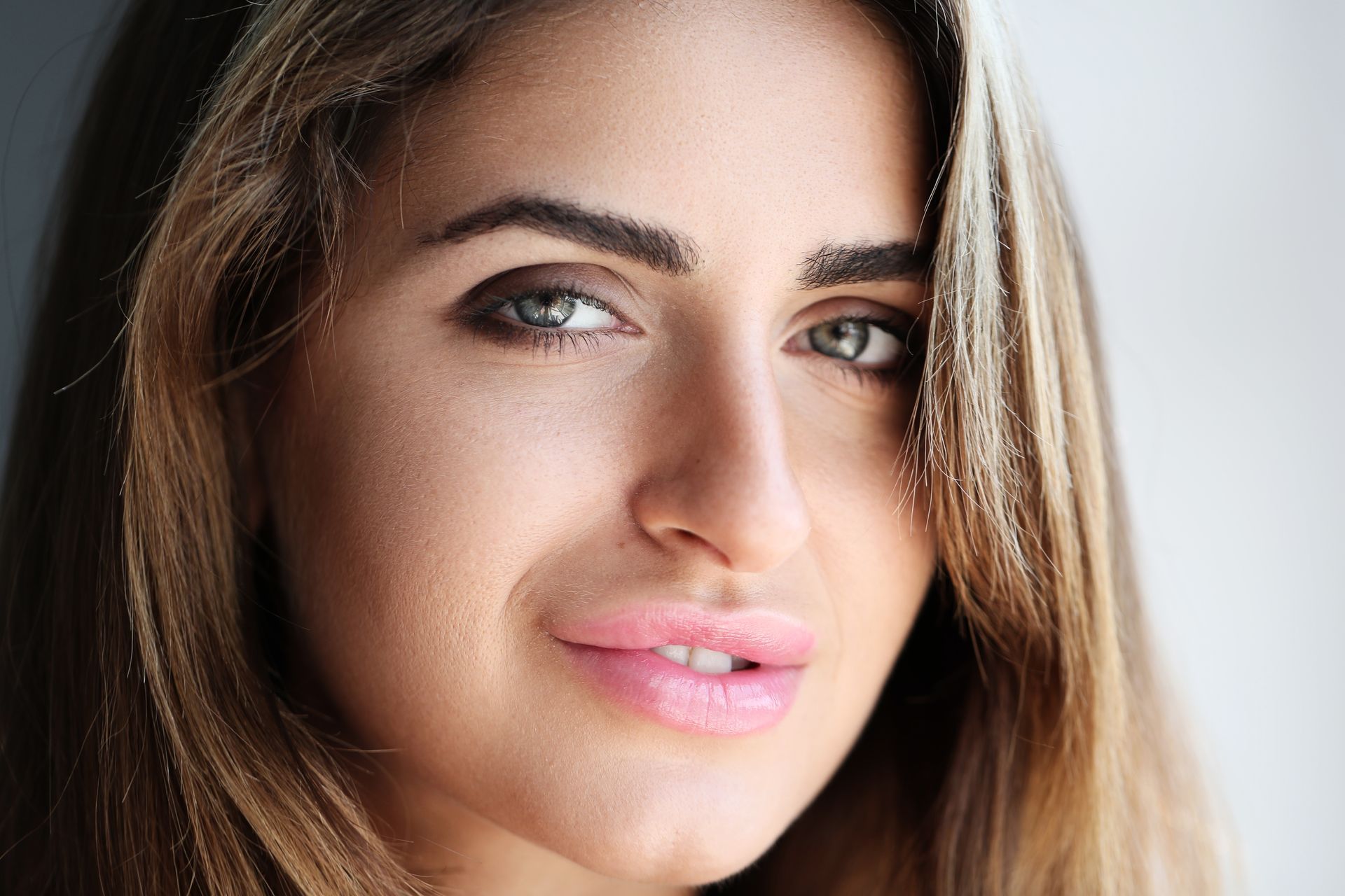 A close up of a woman 's face with long hair and pink lips.