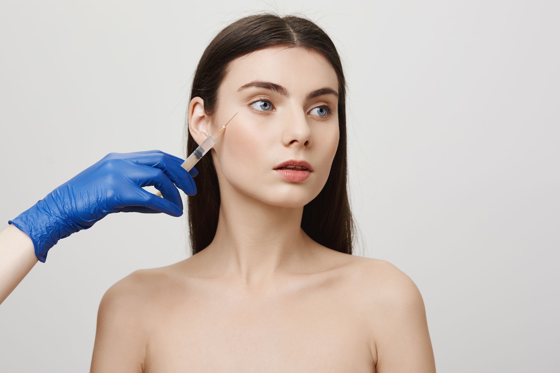 A woman is getting a botox injection in her face.