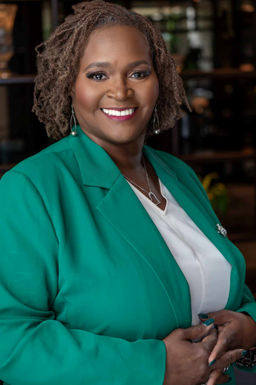 A woman in a blue dress is leaning on a red couch.