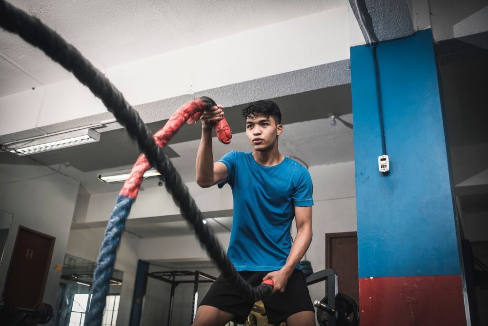 A man is holding a large rope in a gym.