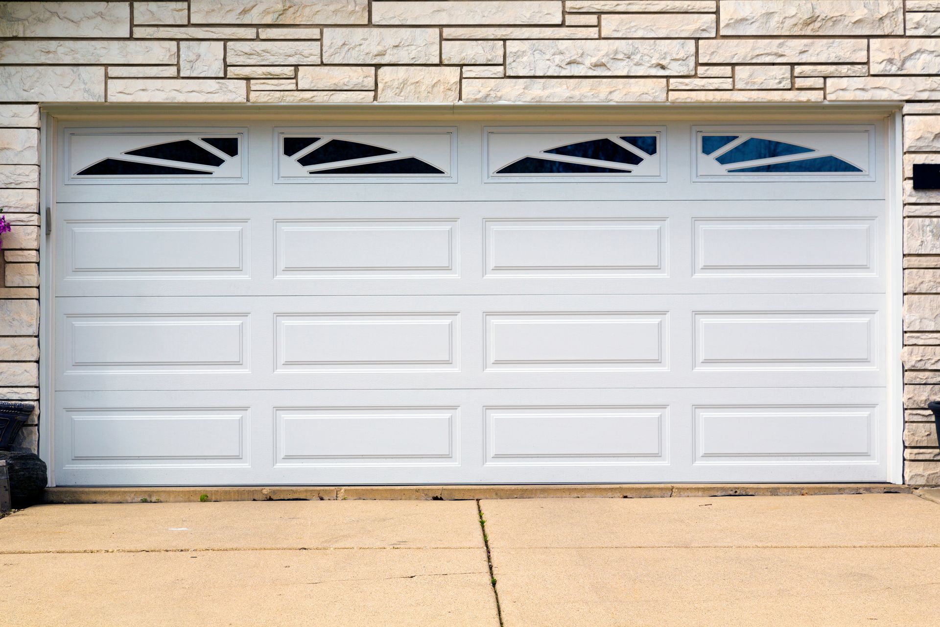 White suburban garage door with four upper windows and a concrete driveway