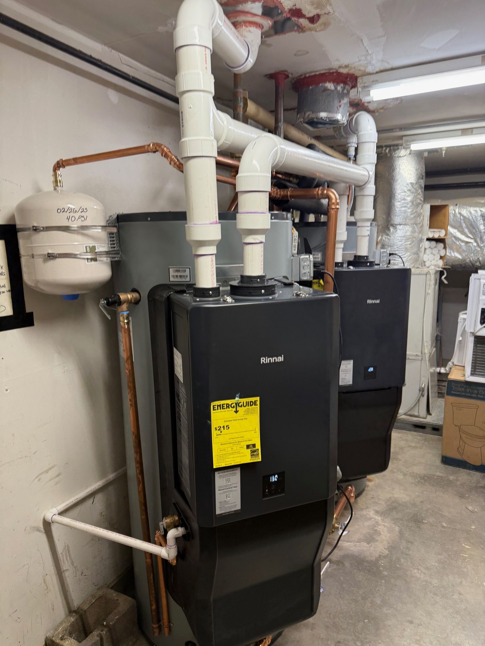 Two boilers are sitting in a room next to each other.