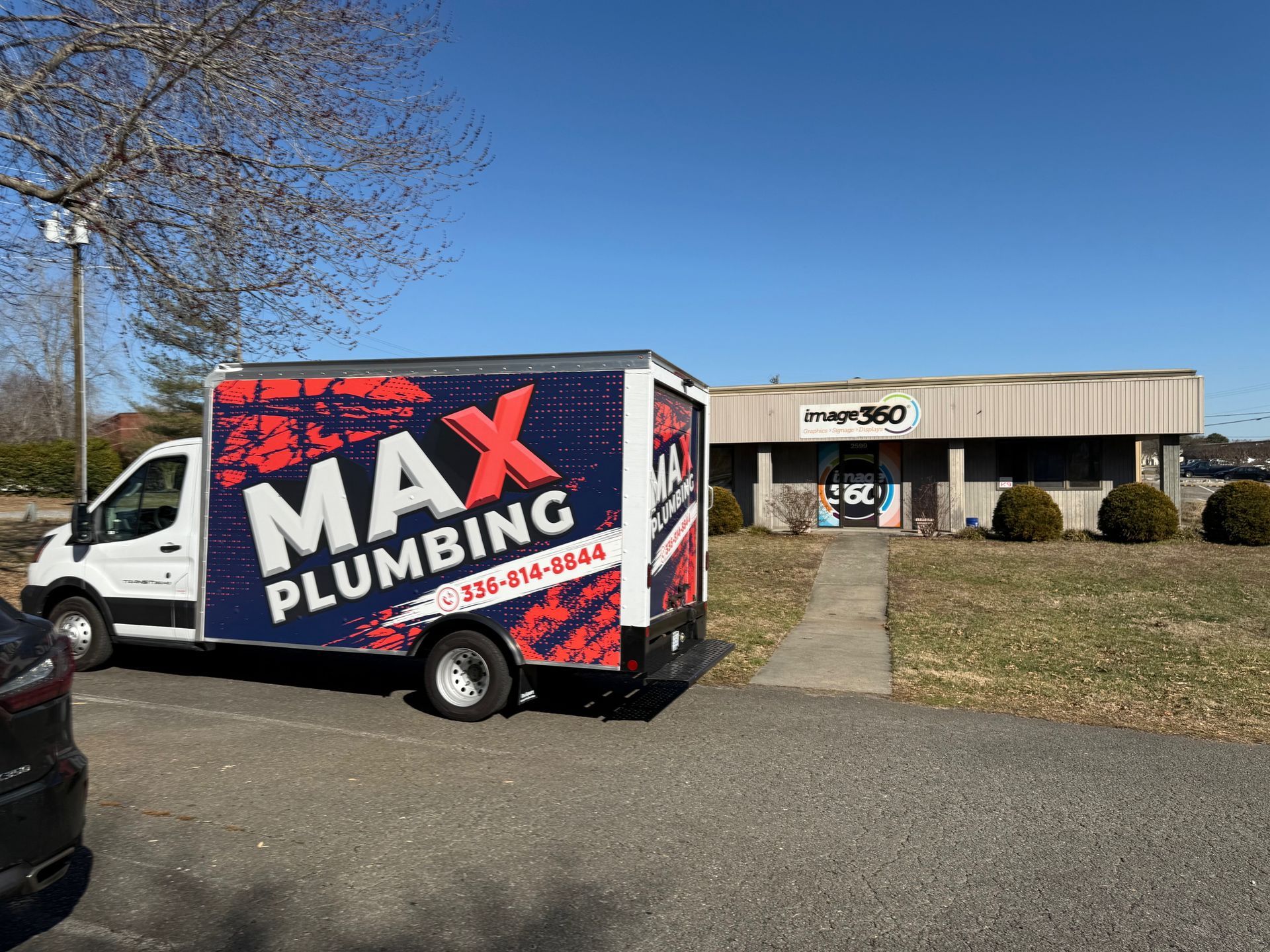 A max plumbing truck is parked in front of a building.