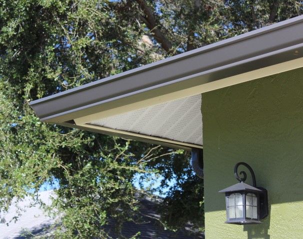 Gray gutters on a green house, with a black lantern on the side.