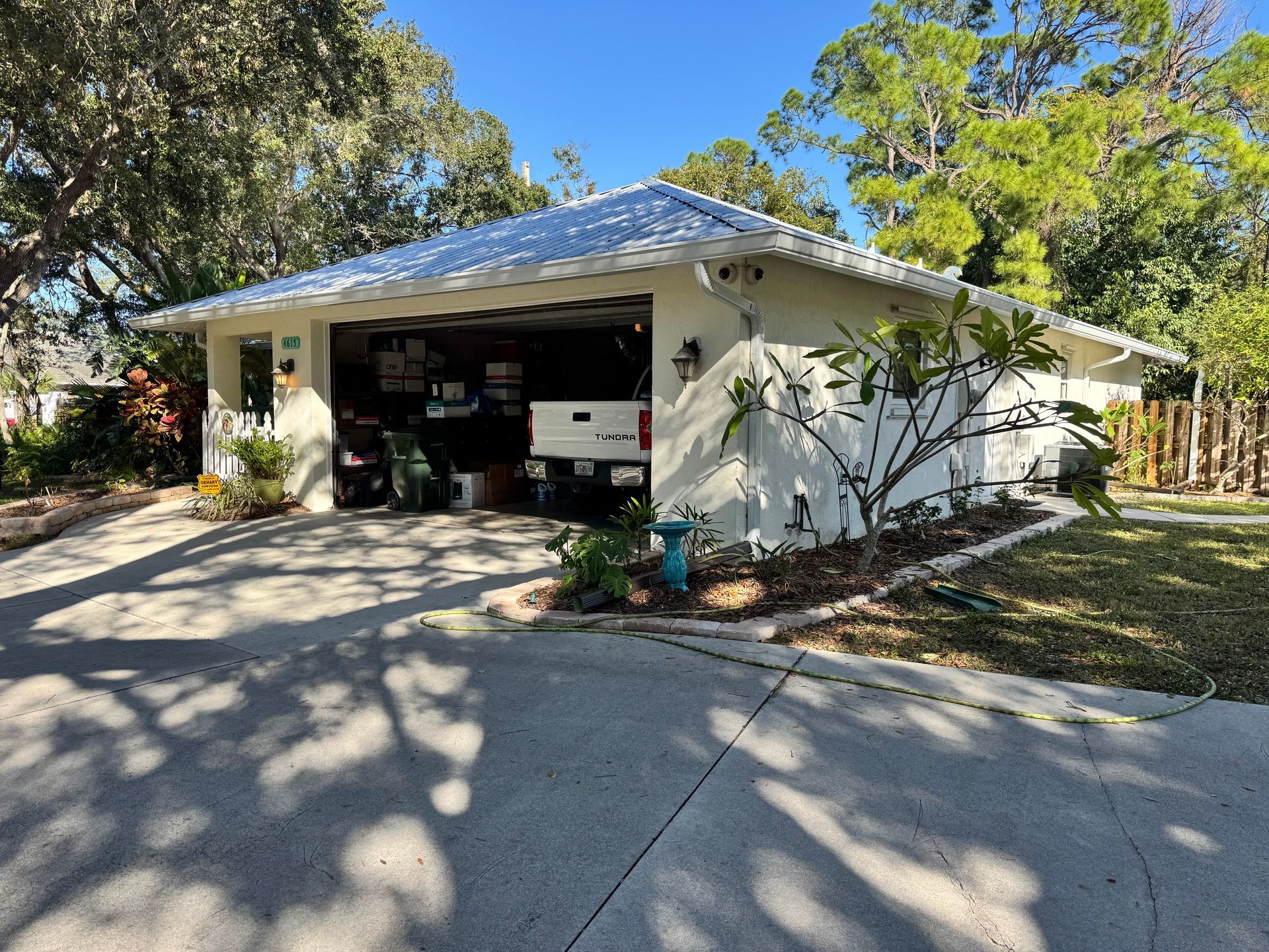 White suburban house with open garage; driveway. Sunny day.