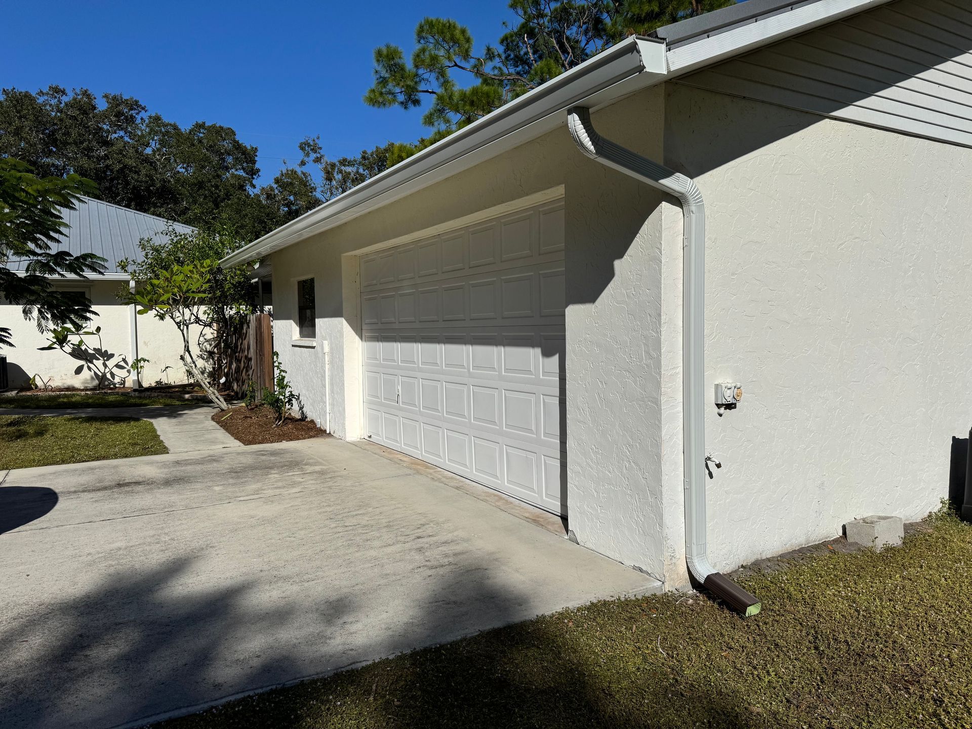 White garage door and building with white gutter and downspout.