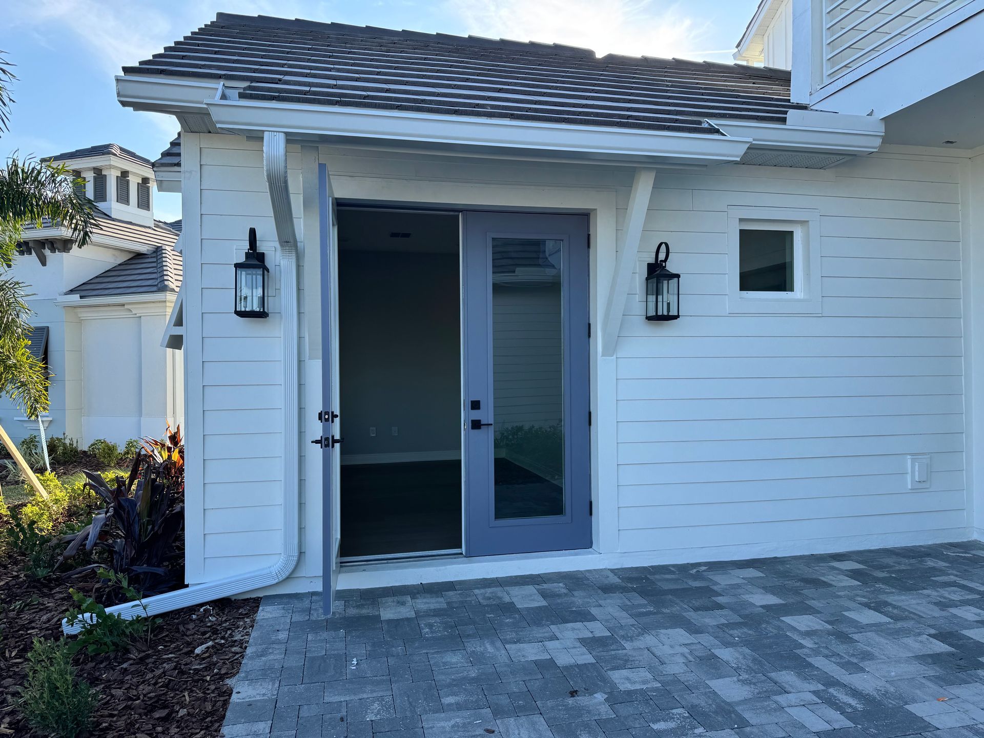 Exterior of white building with purple door. Open door reveals empty room.
