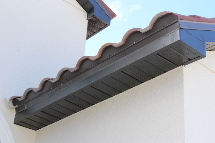Close-up of a house with brown wavy roof tiles, dark brown trim, and a cream-colored exterior wall.