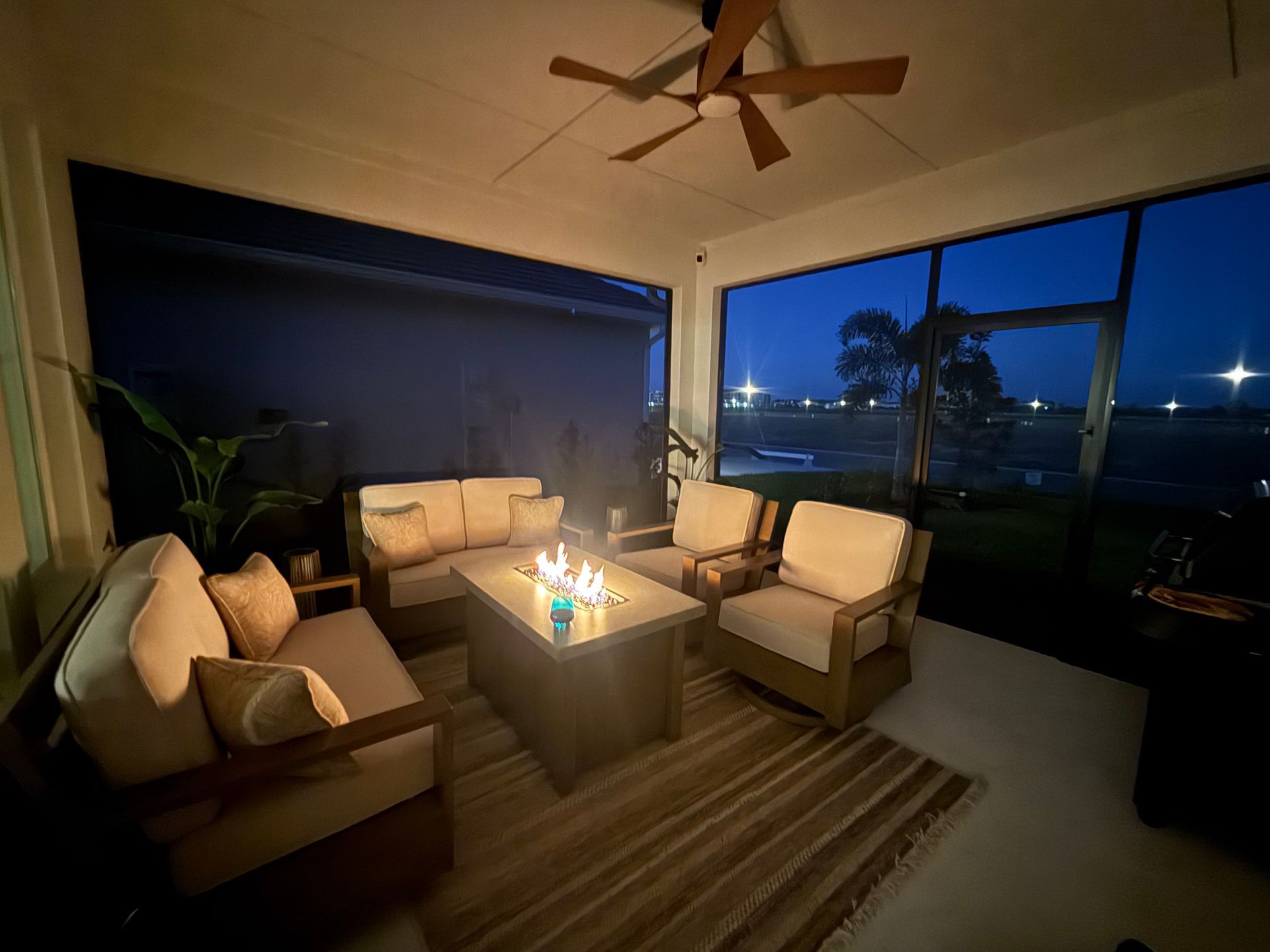 Outdoor patio with lit fire pit, seating, and view of the night sky.