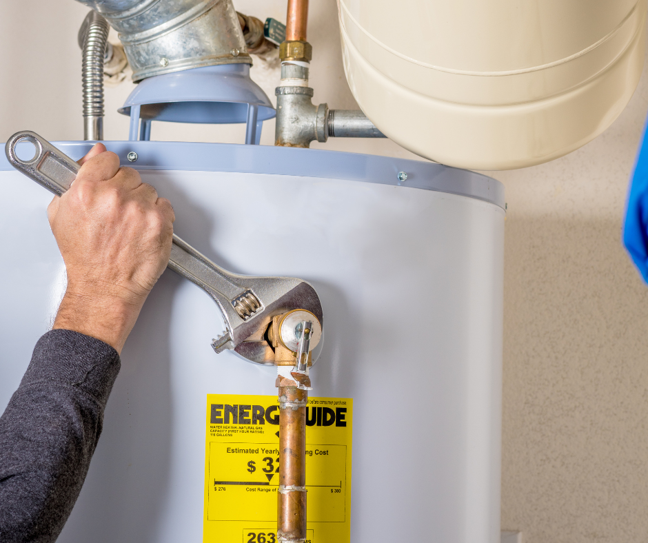 A hand uses an adjustable wrench to tighten a fitting on a white water heater.