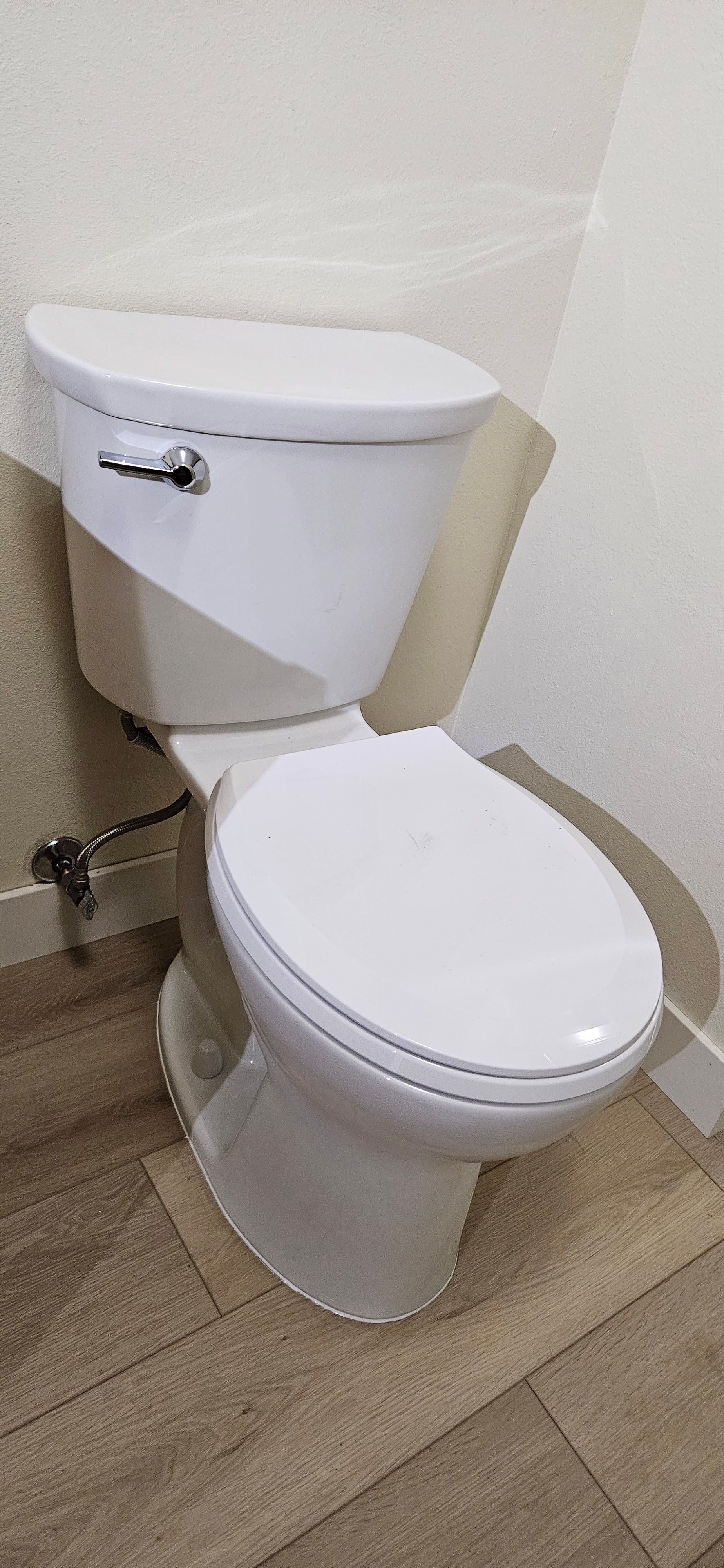 White toilet in a bathroom with light brown tile flooring.