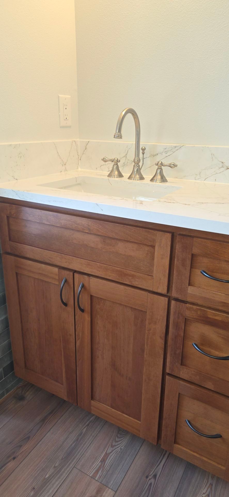 Bathroom sink with wooden cabinets, a white countertop, and a silver faucet.