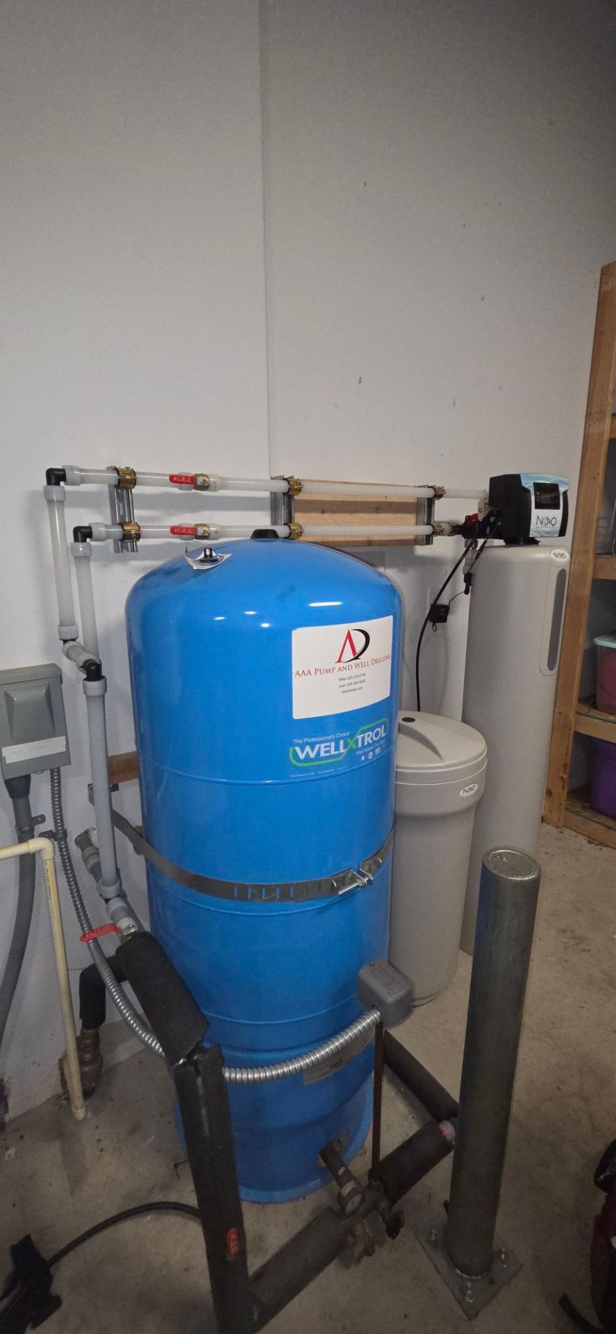 Blue water tank, water filtration system, pipes, and other equipment in a utility space.