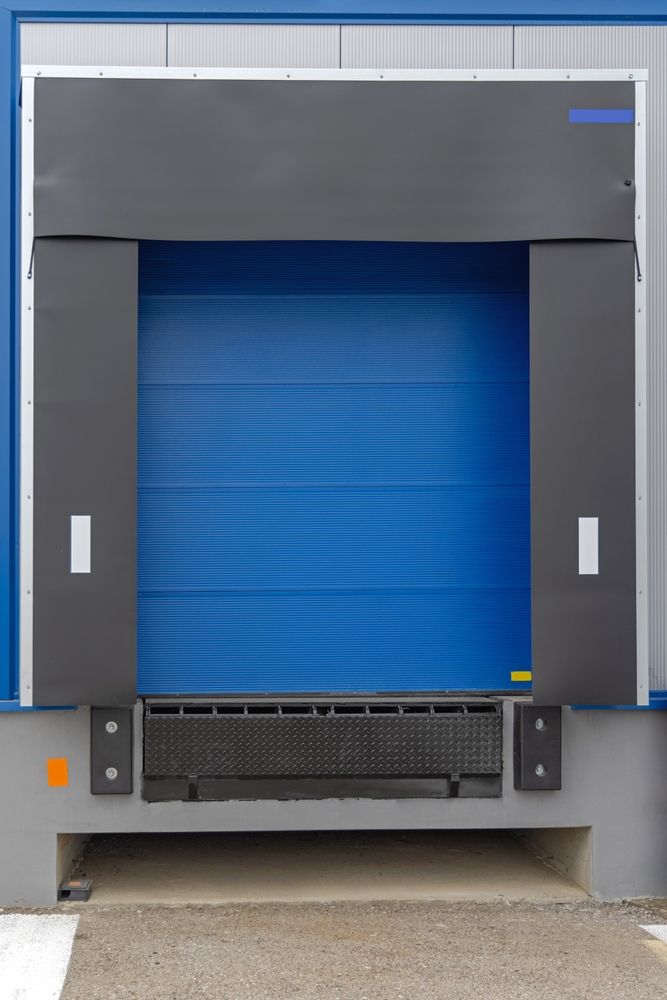 Blue loading dock door with black frame, dock leveler, and blue building exterior.
