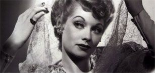 A black and white photo of a woman holding a lace veil.