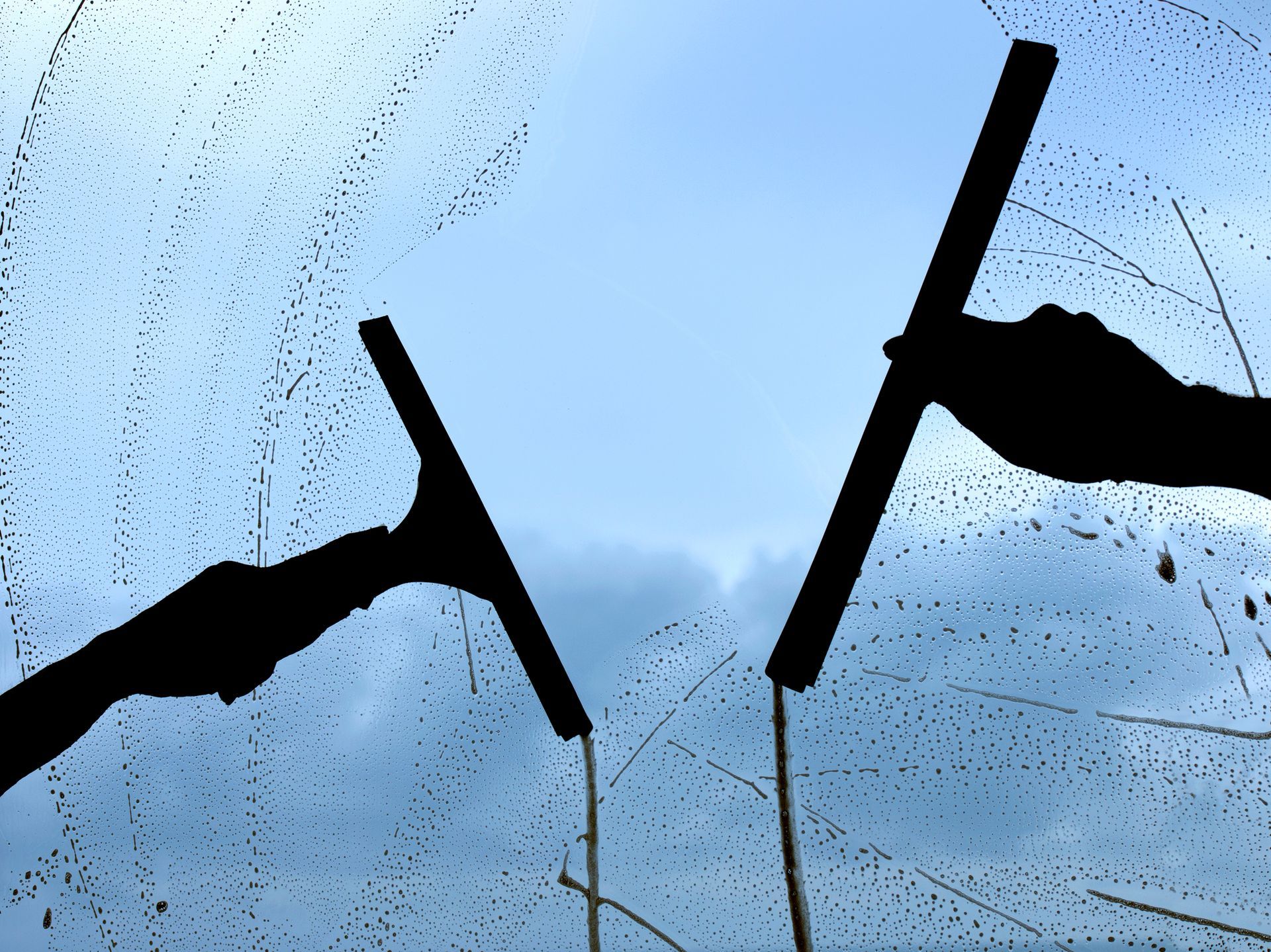 Two people are cleaning a window with a squeegee