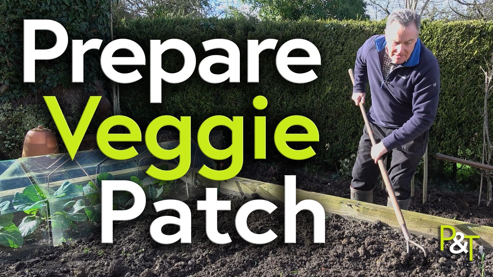 Martin Fish stands with a long handled cultivator tool to the left of the image - he's facing the camera but looking down at the soil in the raised bed he's cultivating. To the left there are some cabbage plants underneath glass cloches and over the top of that is the large green and white text Prepare Veggie Patch.