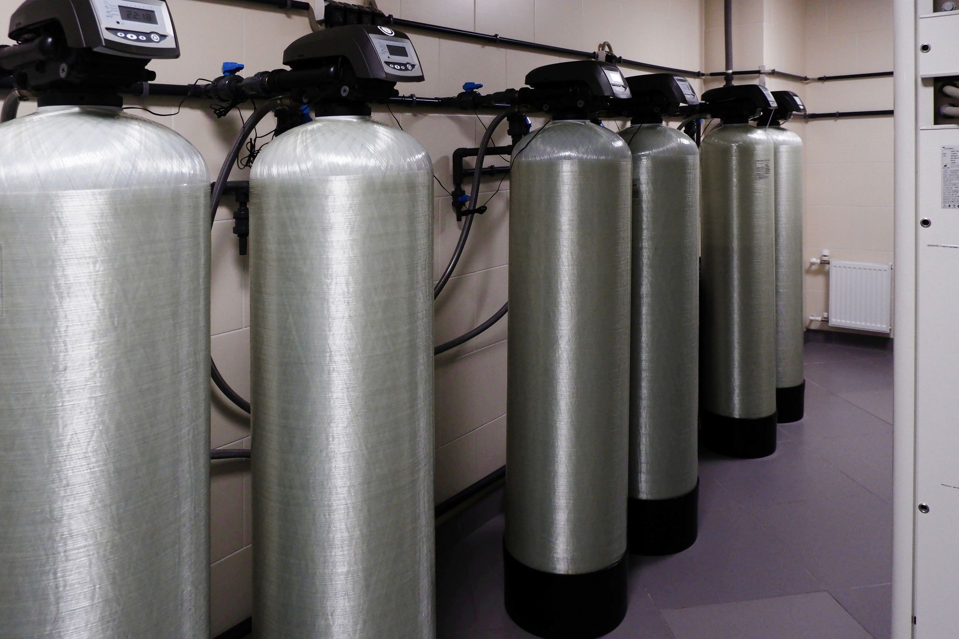Row of water filtration tanks with control panels in an industrial setting.