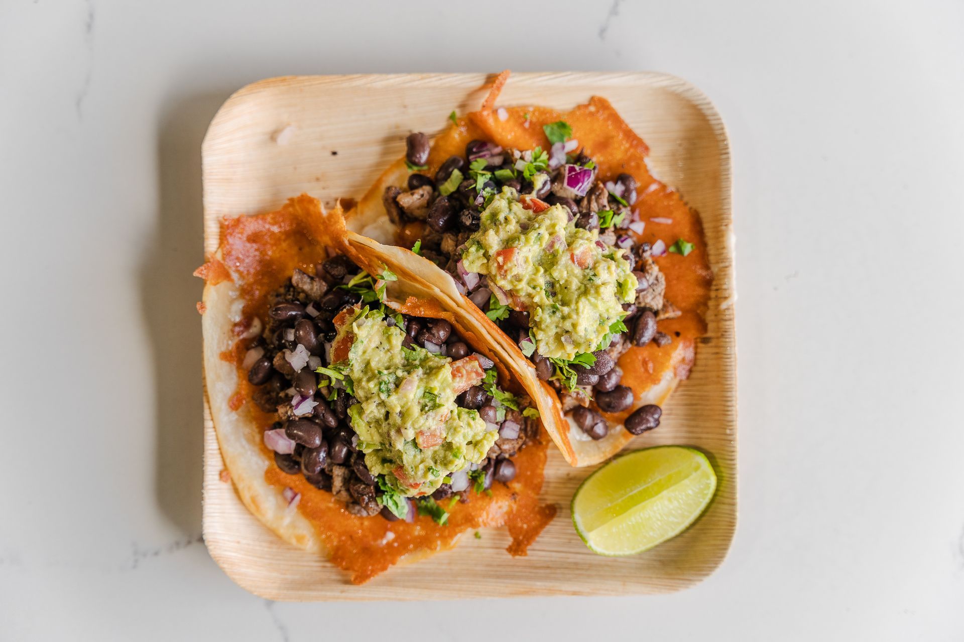 Carne asada taco perron with beans, guacamole, red onions and crispy cheese by chubasco tacos