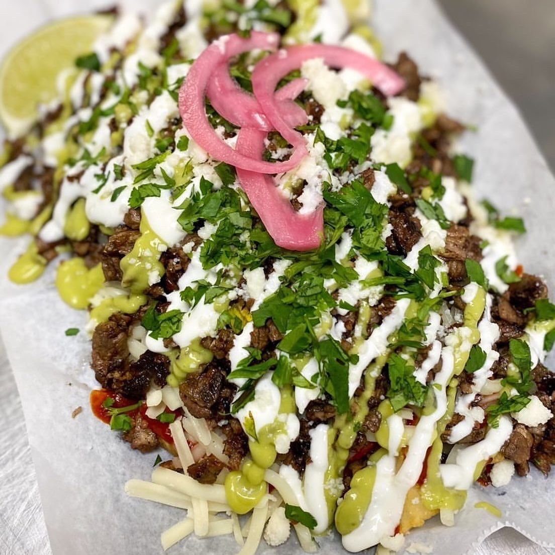 Carne asada fries loaded with queso, crema, pickled onions, and fresh cilantro