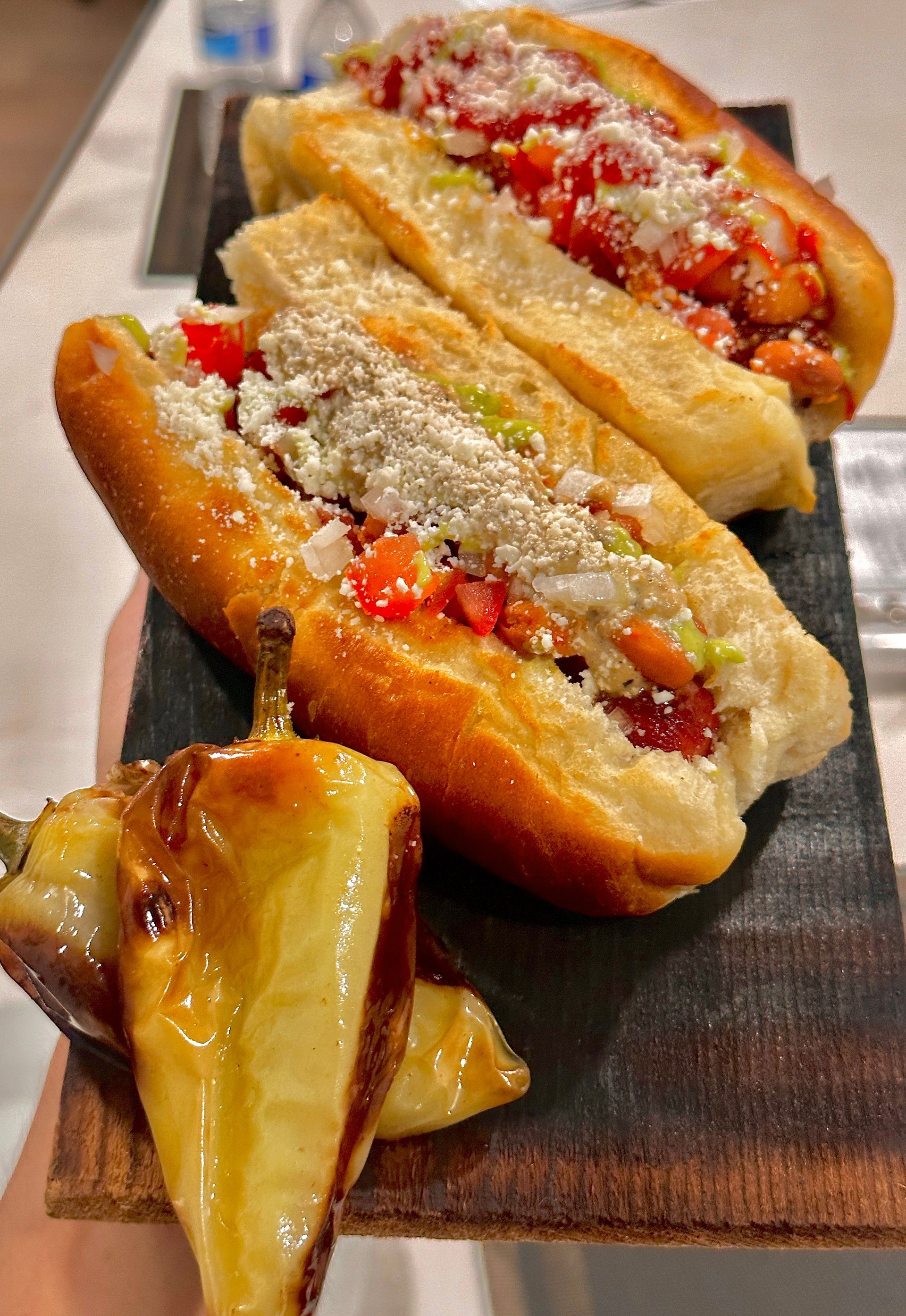 Bacon-wrapped Sonoran hot dogs topped with beans, jalapeños, crema, and salsa