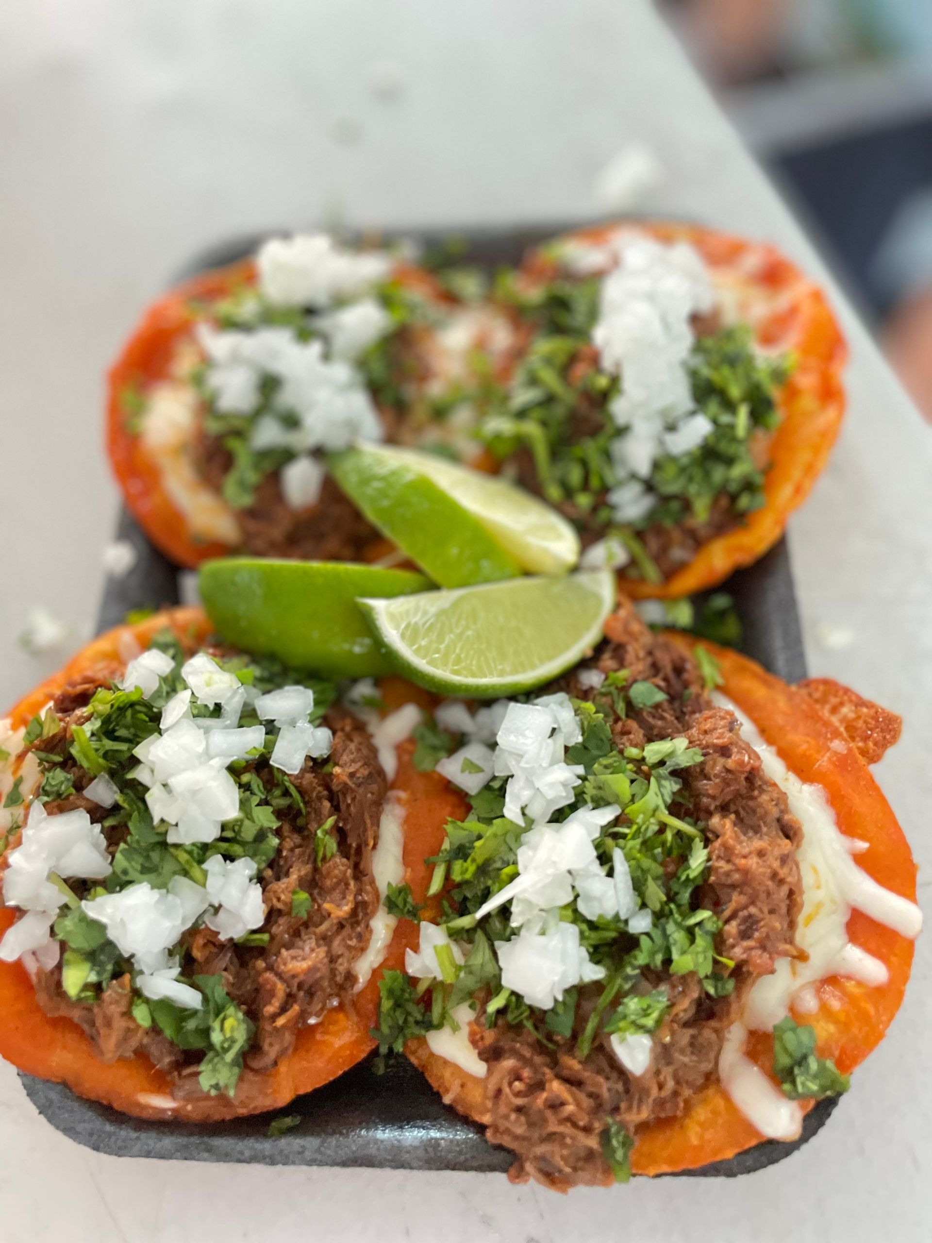birria de res quesotacos topped with onions and cilantro at Chubasco Tacos