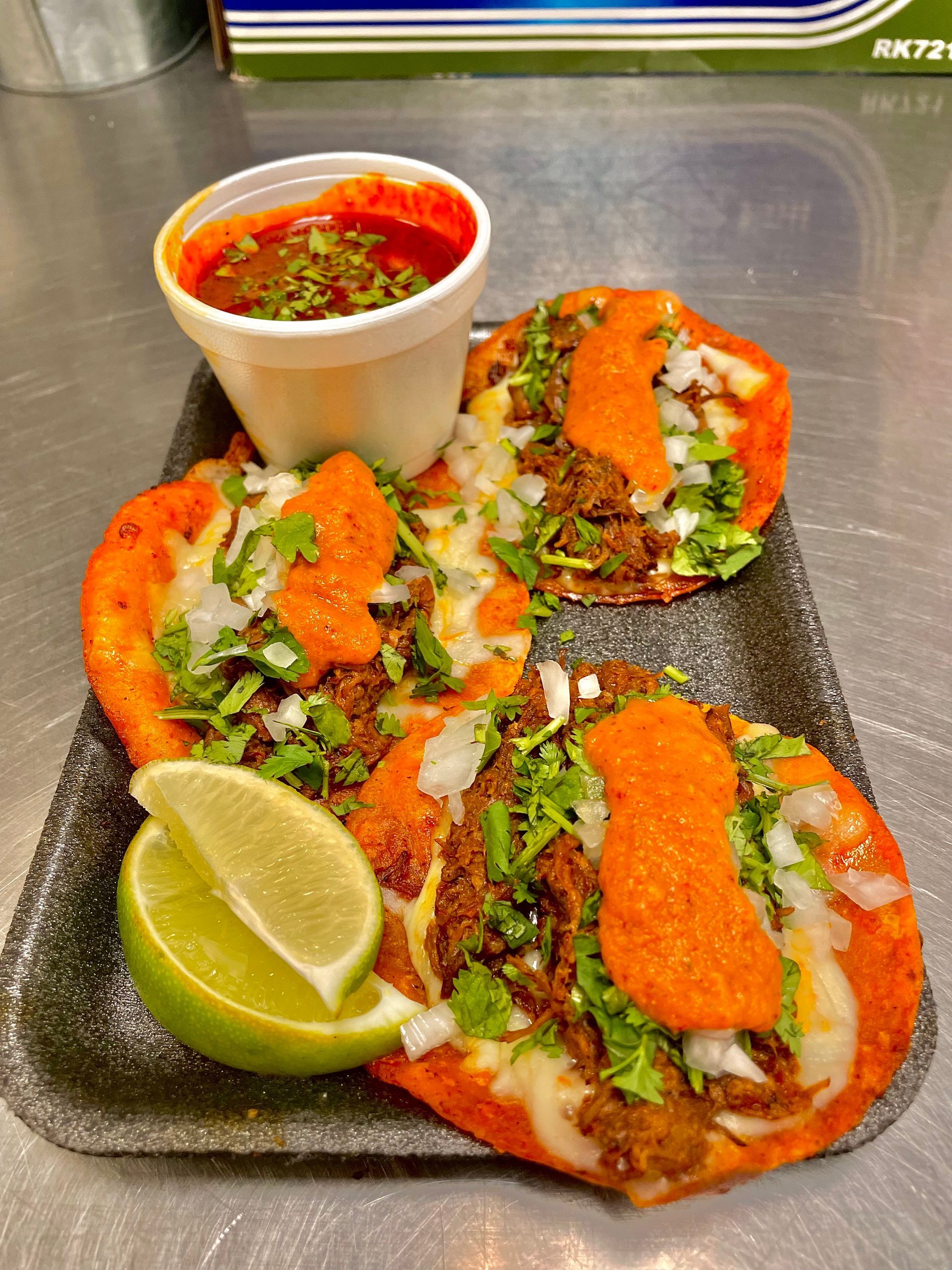 Crispy birria taco dipped in consommé, topped with onions and cilantro at Chubasco Tacos