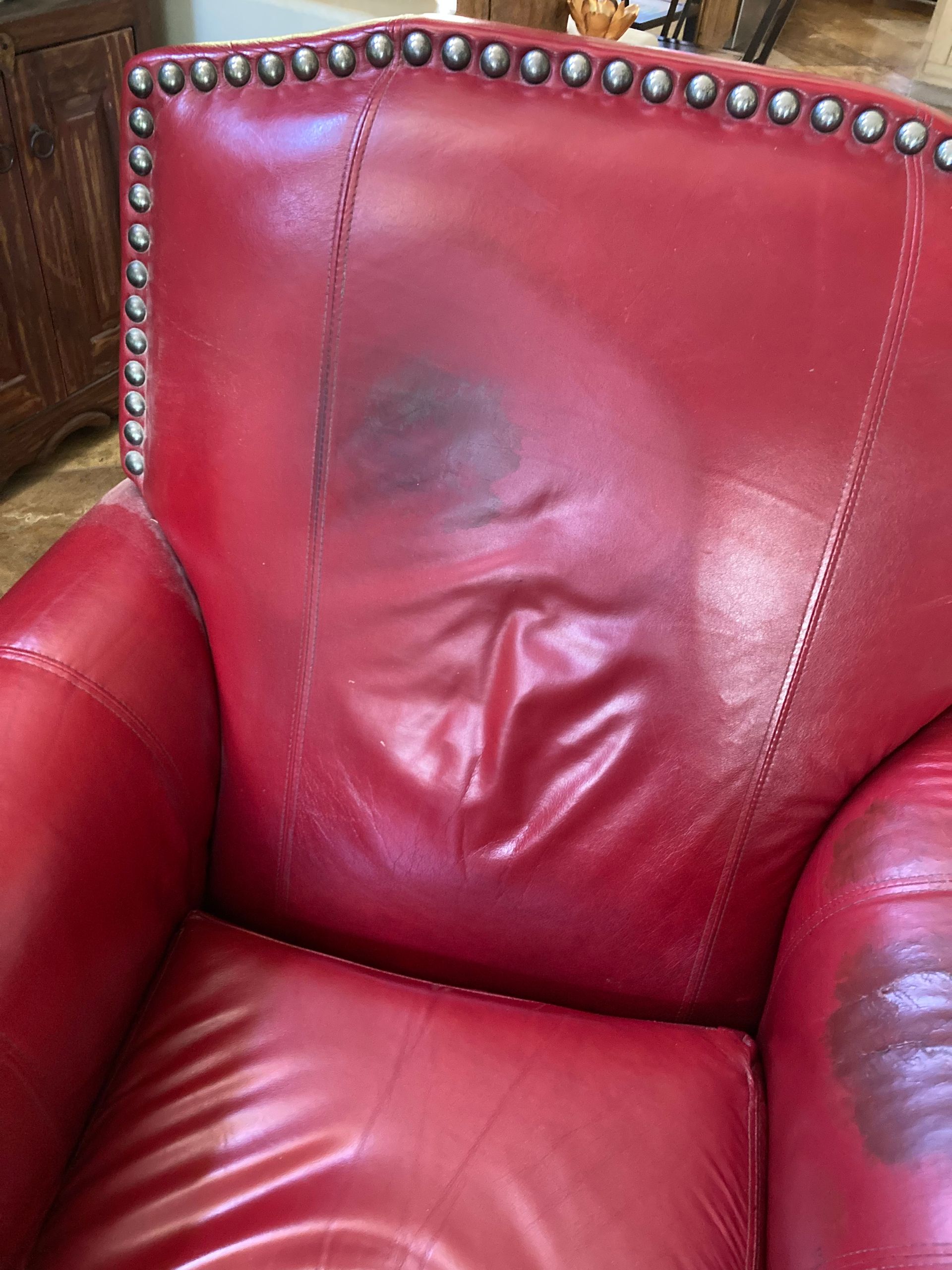 Red leather armchair with dark stain on back.