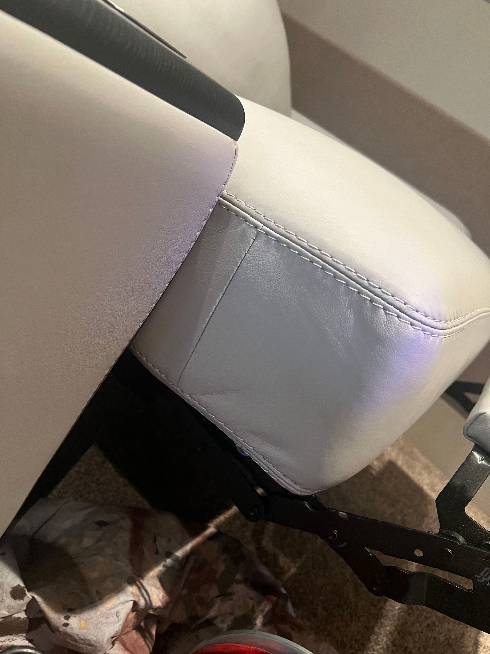 White leather chair detail; corner with stitching, black frame.