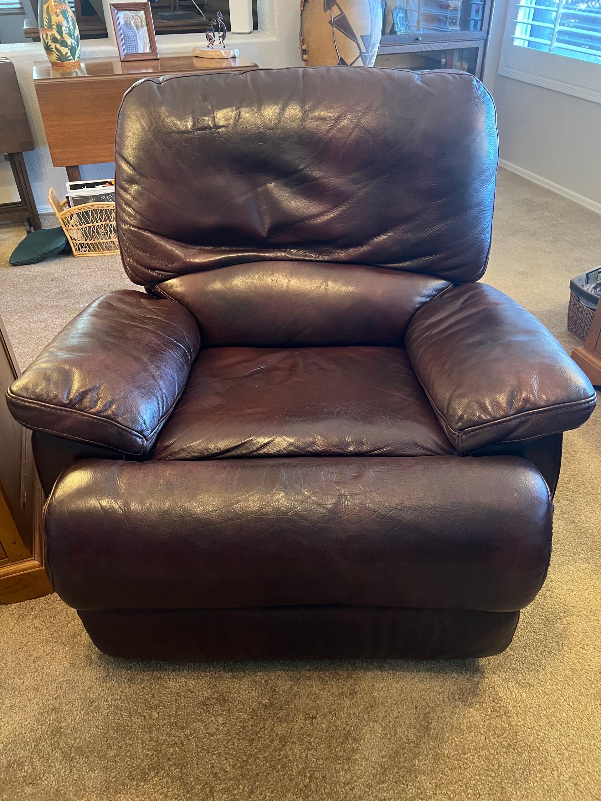 Dark brown leather recliner chair in a living room setting.