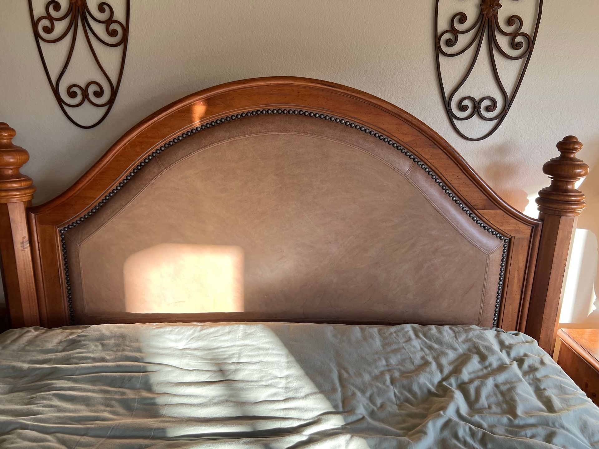 Wooden bed with a beige upholstered headboard, floral wall decor.