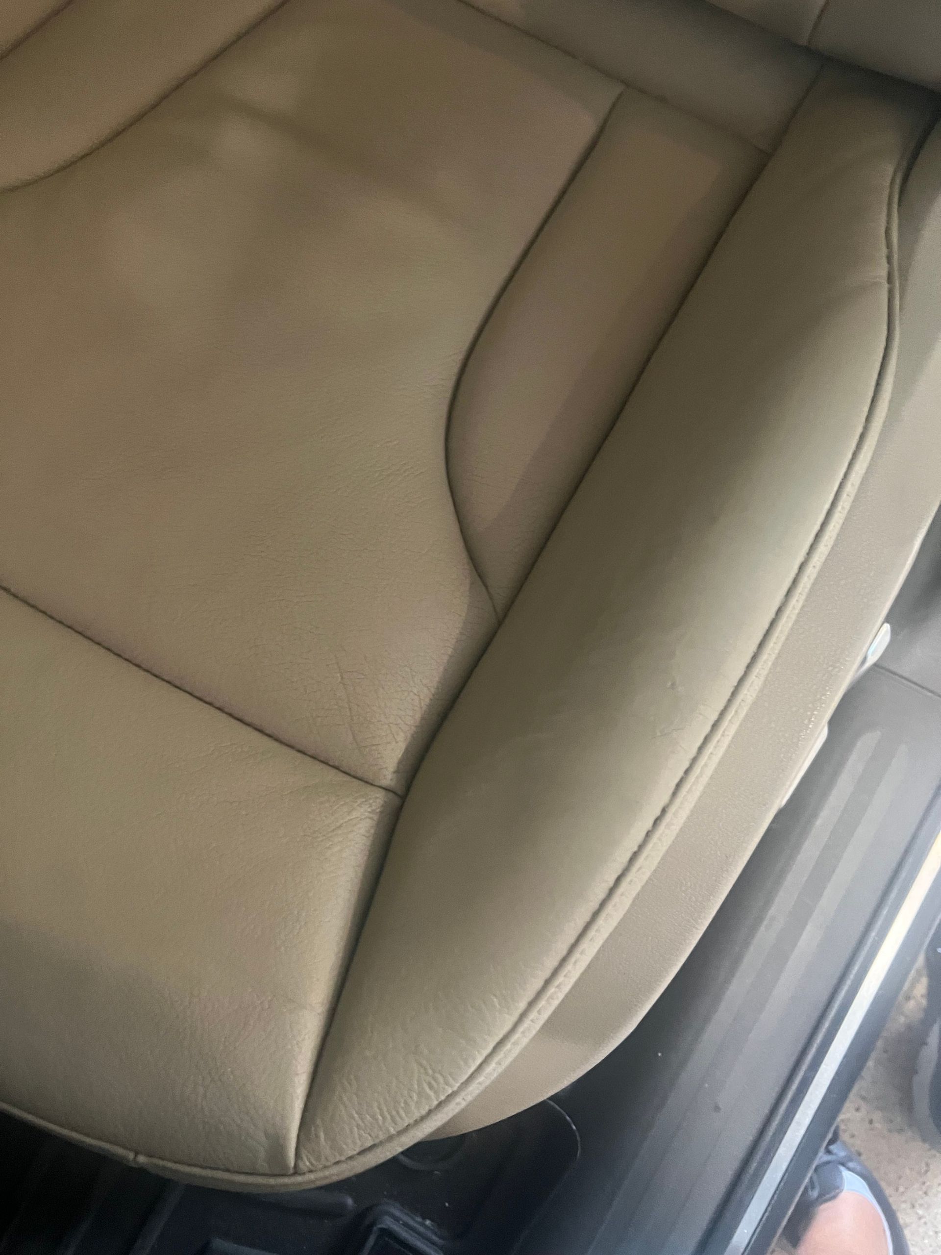 Tan leather car seat with stitching details.