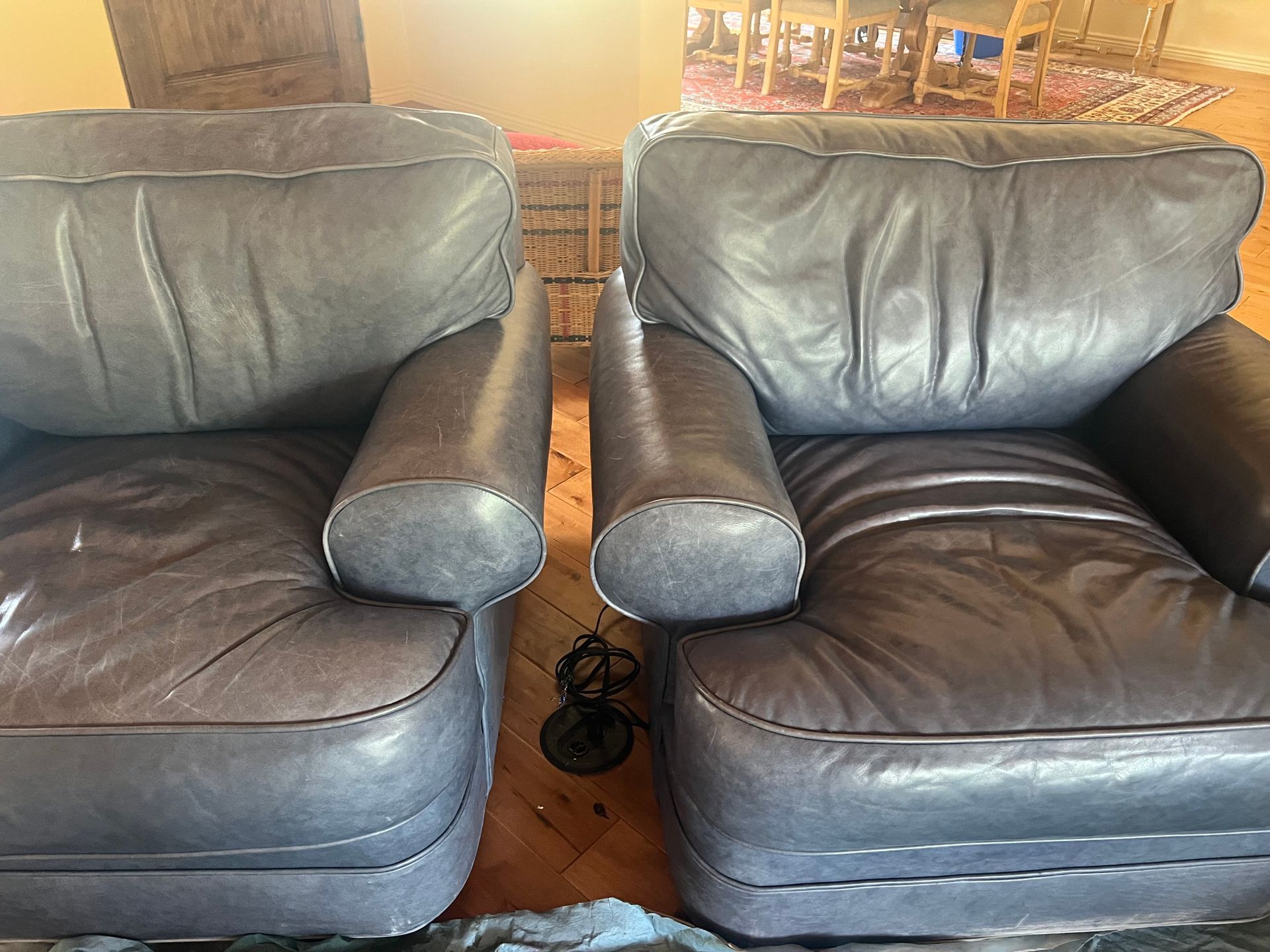 Two gray leather armchairs side-by-side on a wood floor.