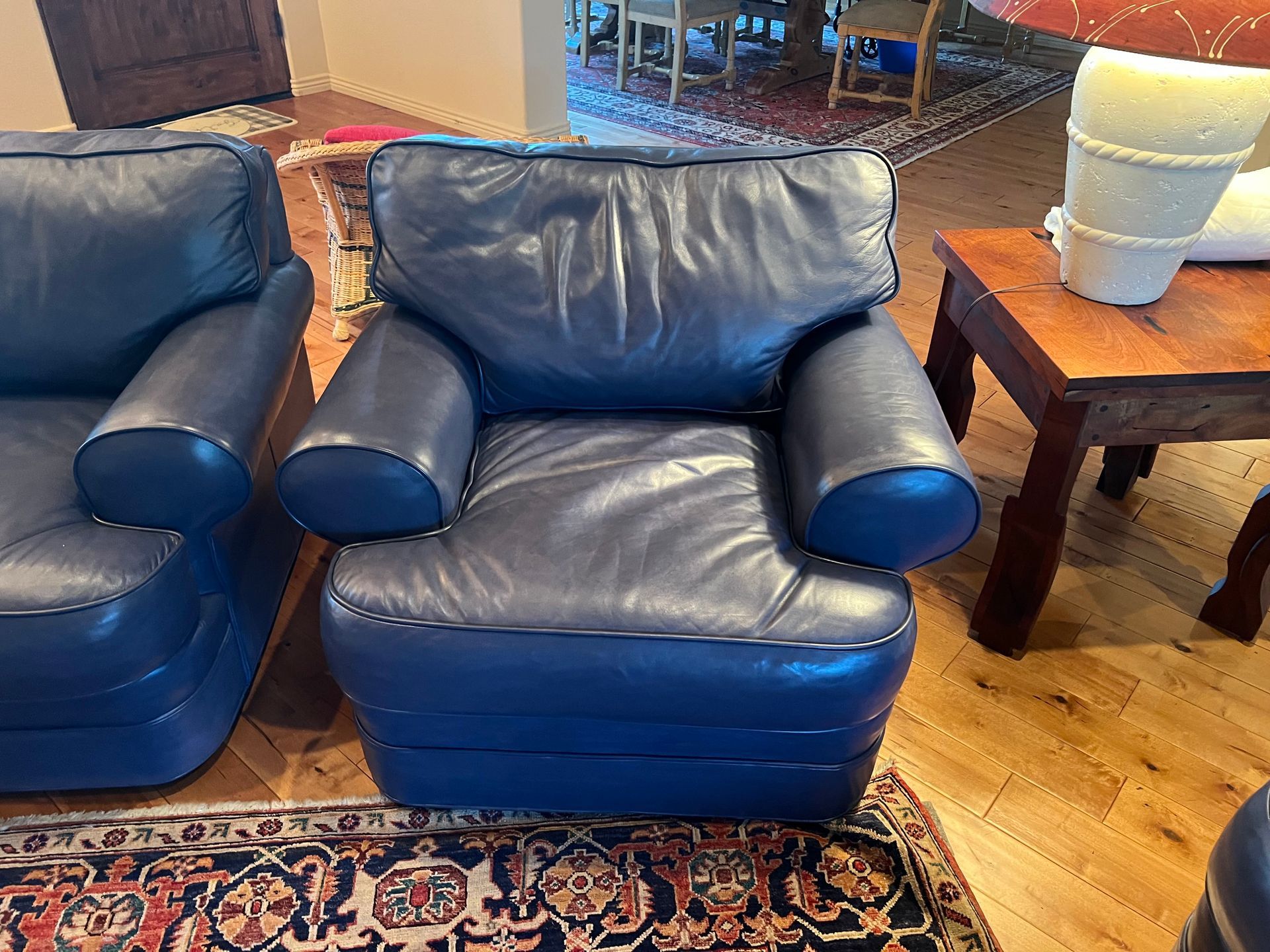 Blue leather armchair on patterned rug, next to a small wooden table.