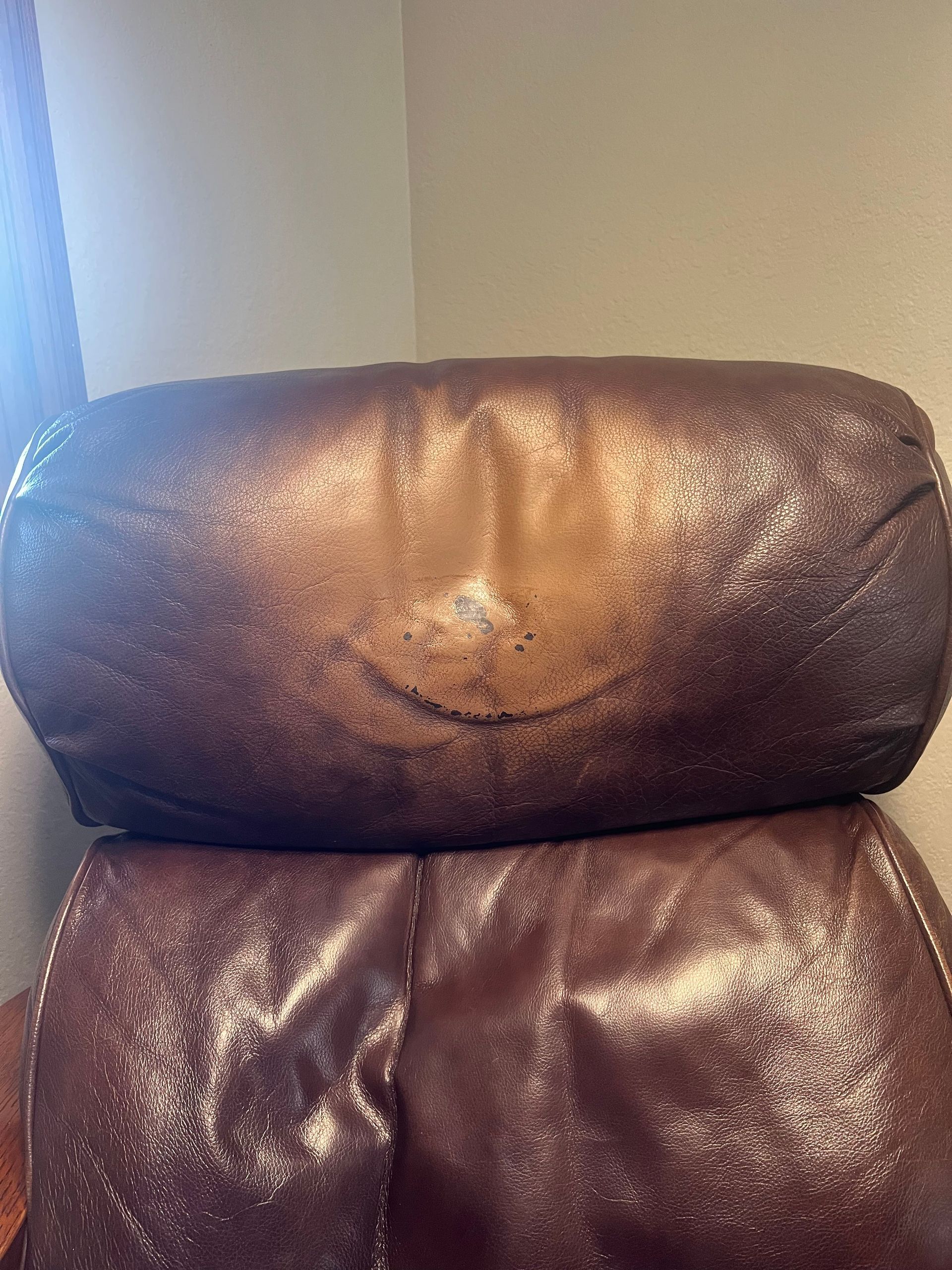 Brown leather recliner with visible wear on the headrest.