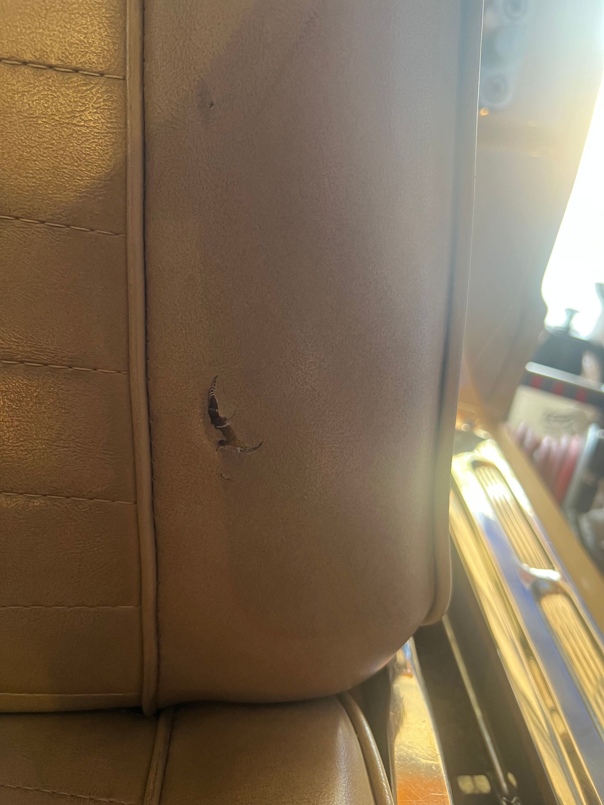 Tan car seat with a small tear.