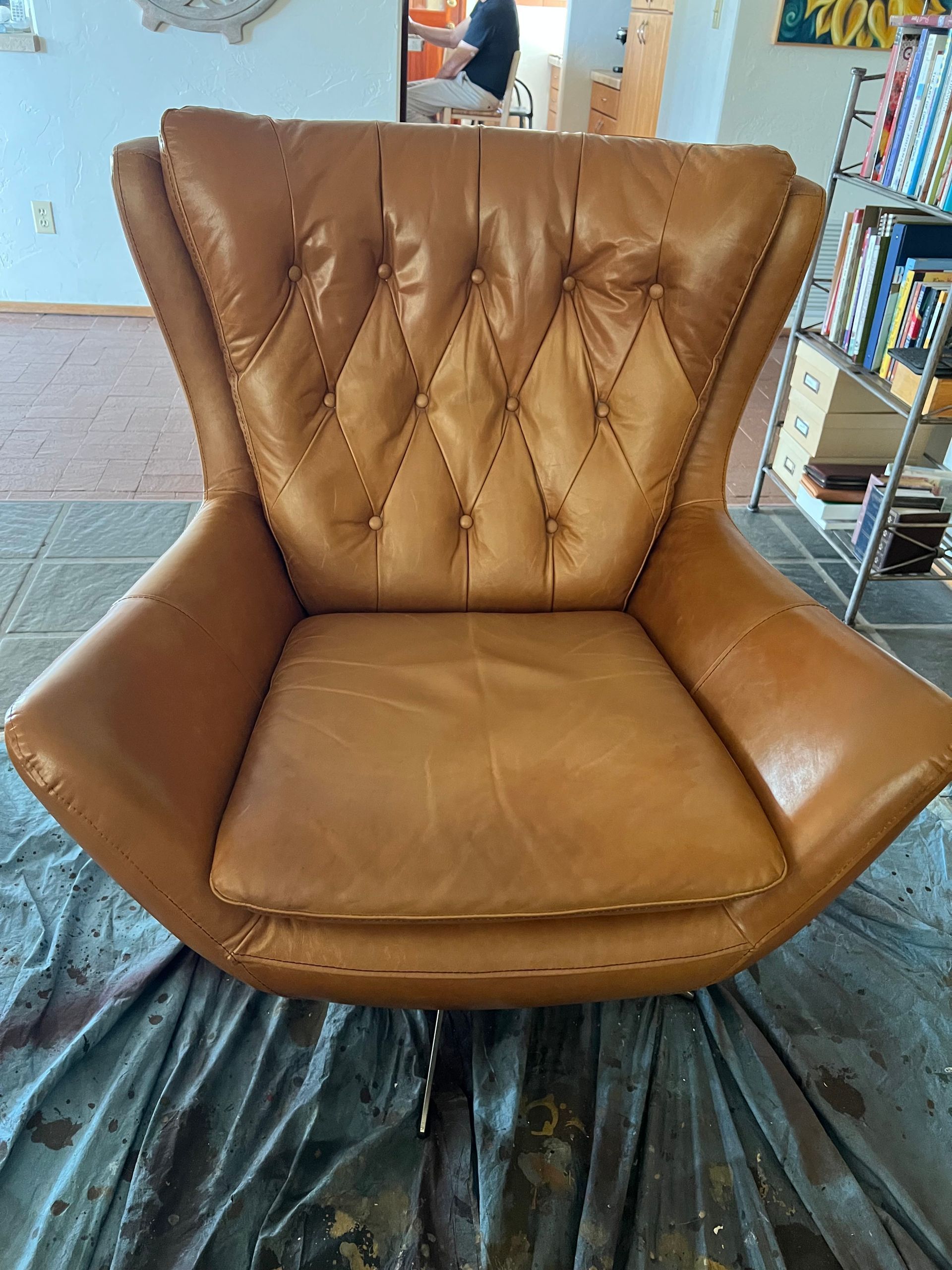 Brown leather armchair with button details, on a tarp.