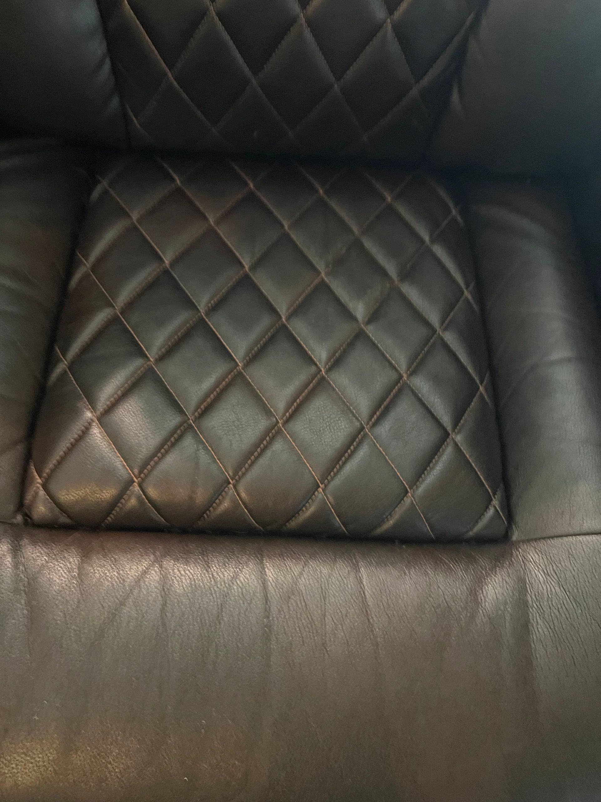 Dark brown leather chair with diamond-patterned stitching on the seat and headrest.